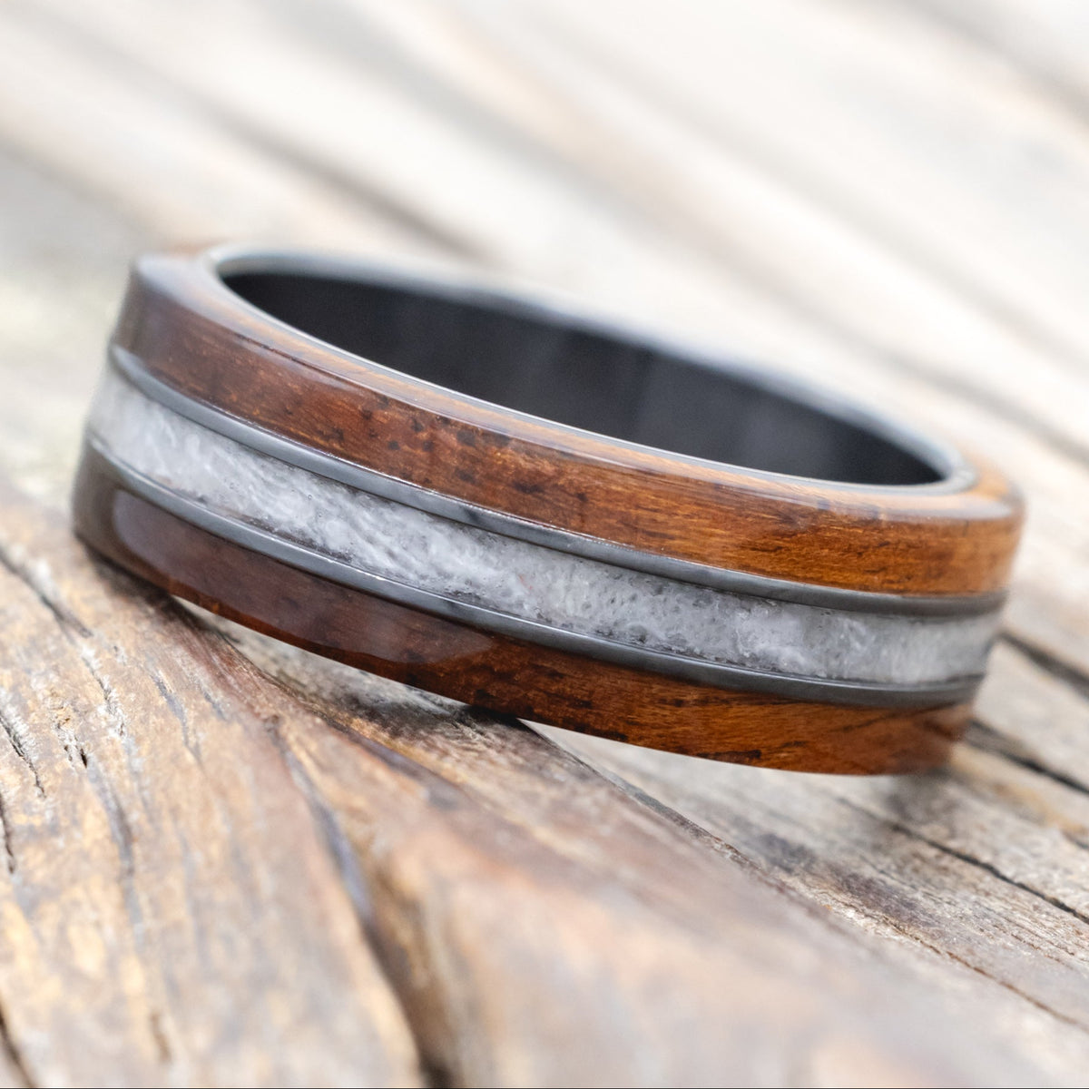 black zirconium wedding ring with koa wood and wedding dress inlay on wooden surface