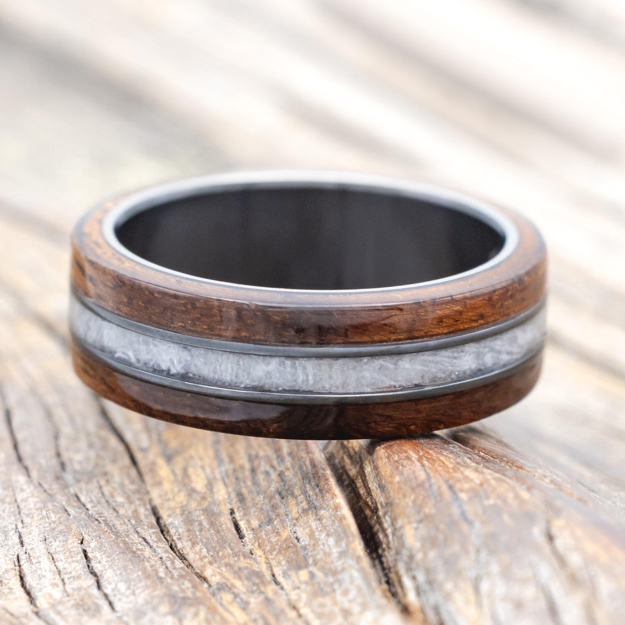 black zirconium wedding ring with koa wood and wedding dress inlay on wooden surface