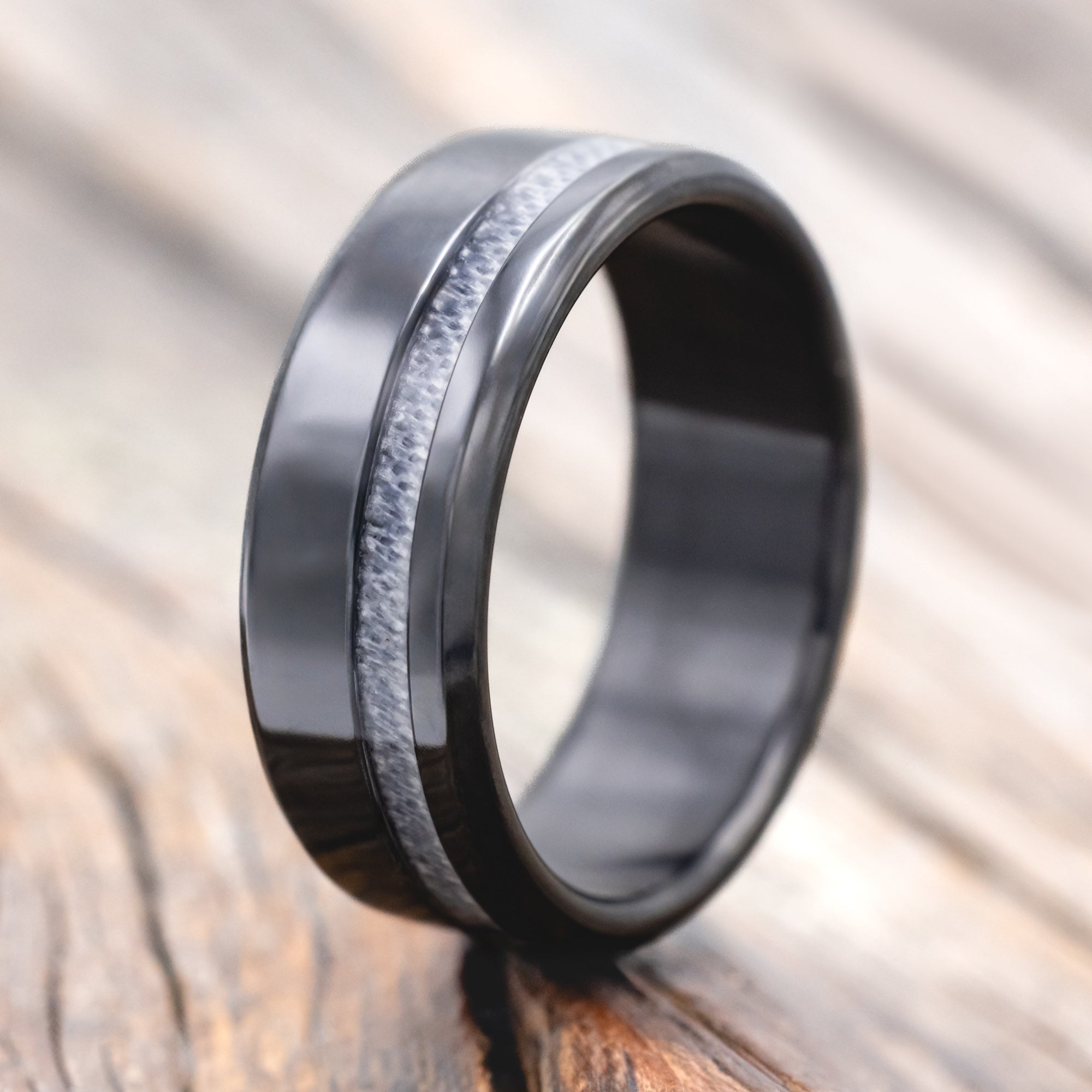 black zirconium wedding ring with wedding dress inlay on wooden surface