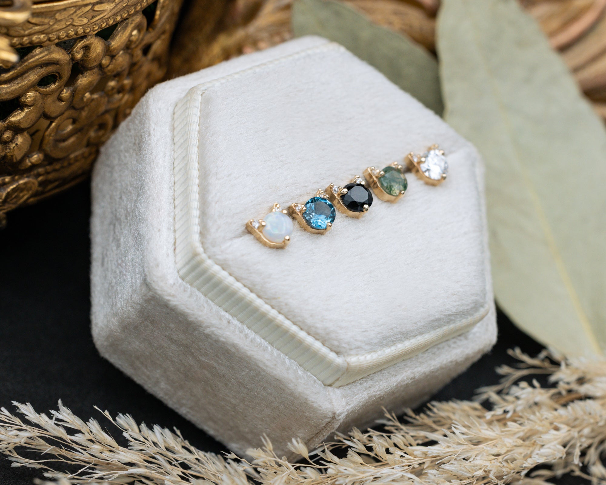 5 cat-shaped stud earrings on a white cushion against a decorative background