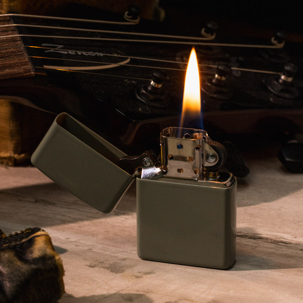 Zippo lighter with flame on a wooden surface with a blurred natural background