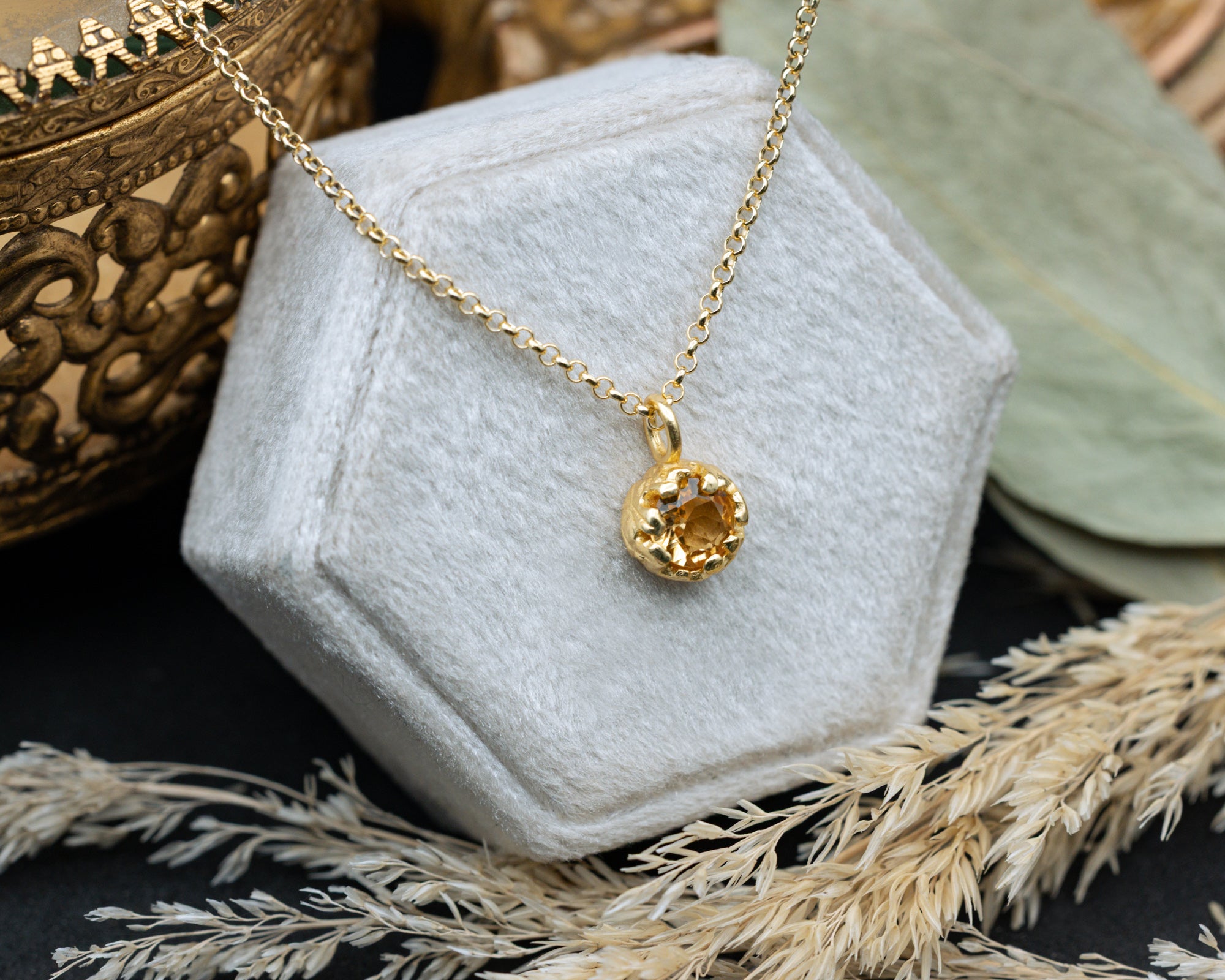Gold necklace with a citrine on a white jewelry box