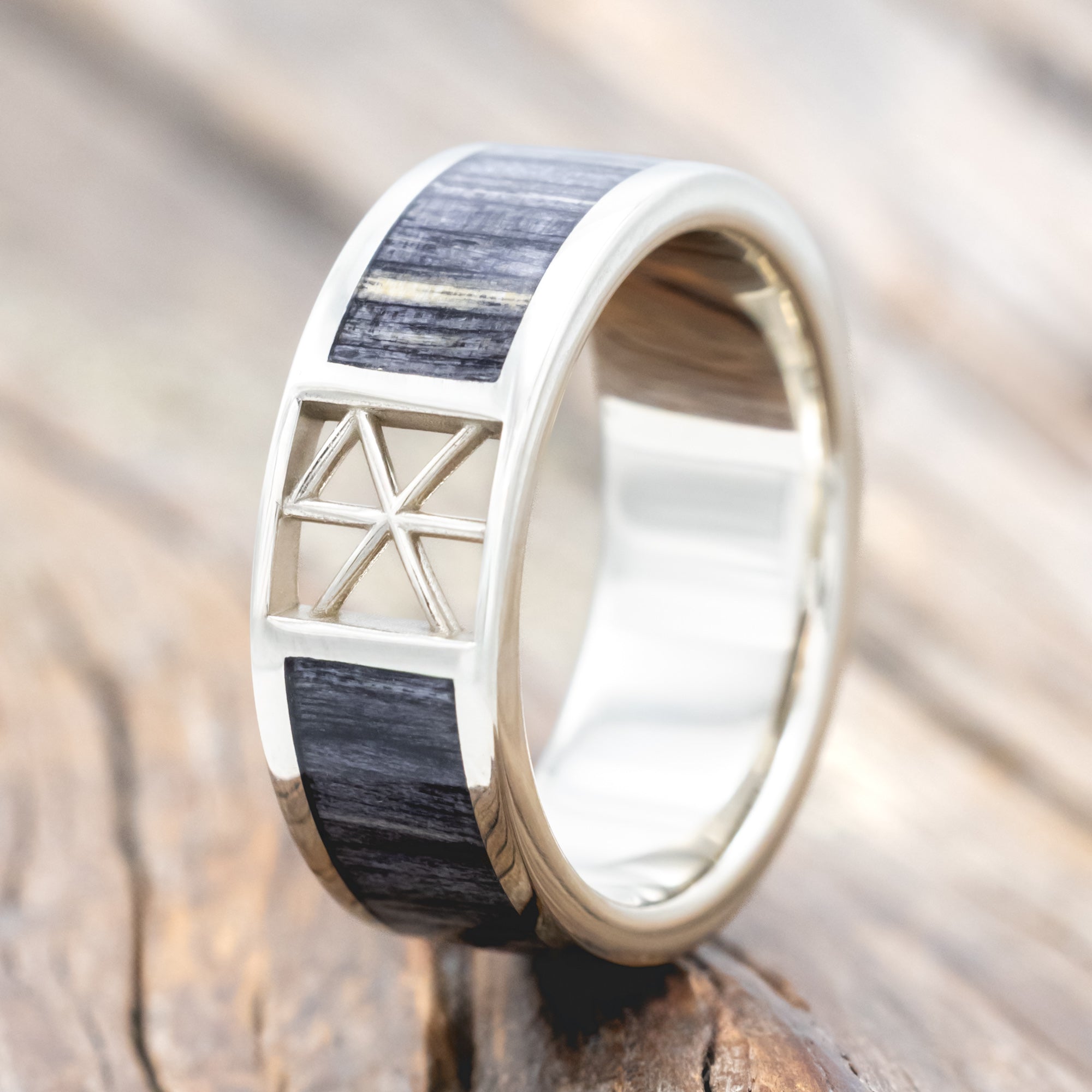 White gold ring with wooden inlay and rune cutout on a wooden surface