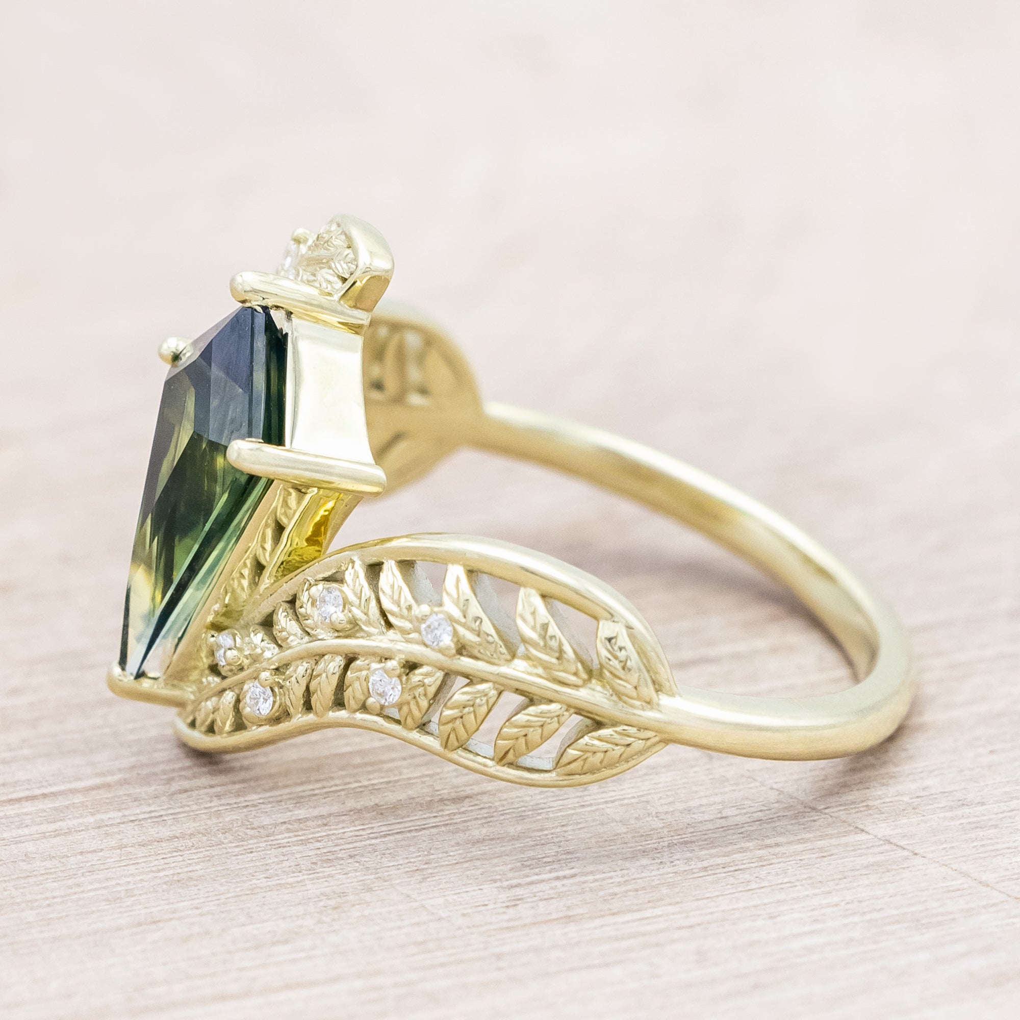 Green gold ring with a green sapphire on a light wooden surface