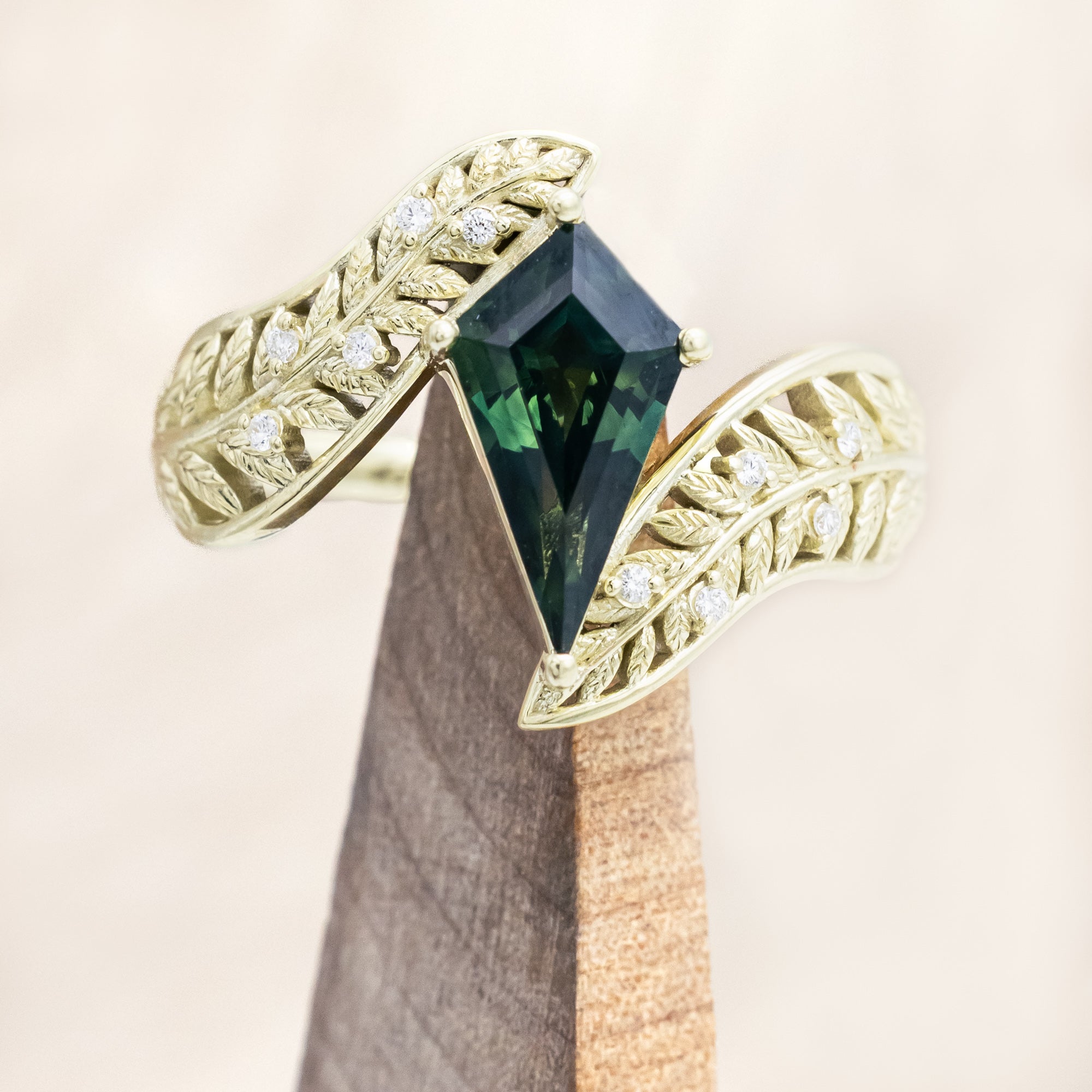 Green gold ring with a green sapphire on a wooden stand against a beige background