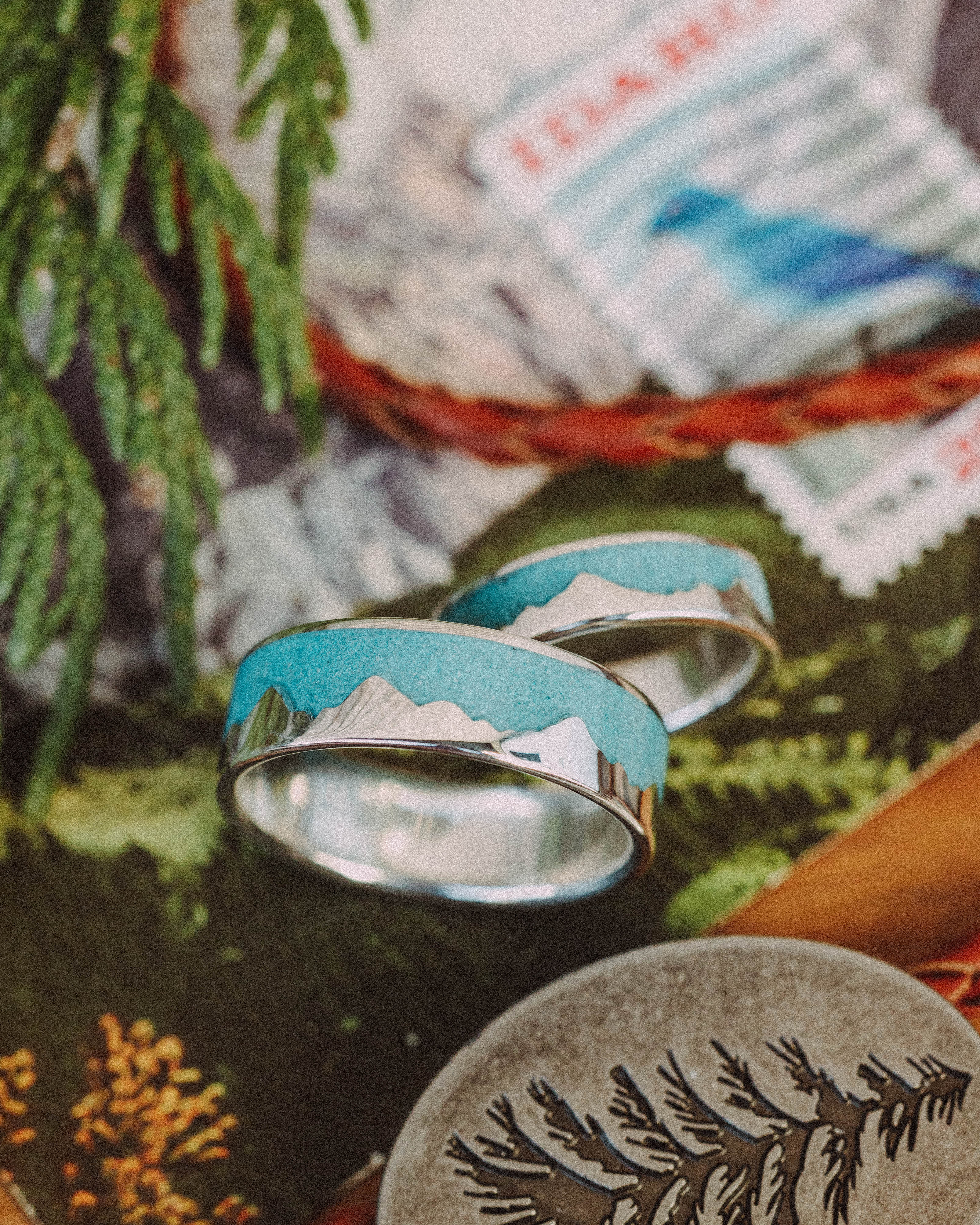 Two silver rings with turquoise inlay against a blurred postcard background