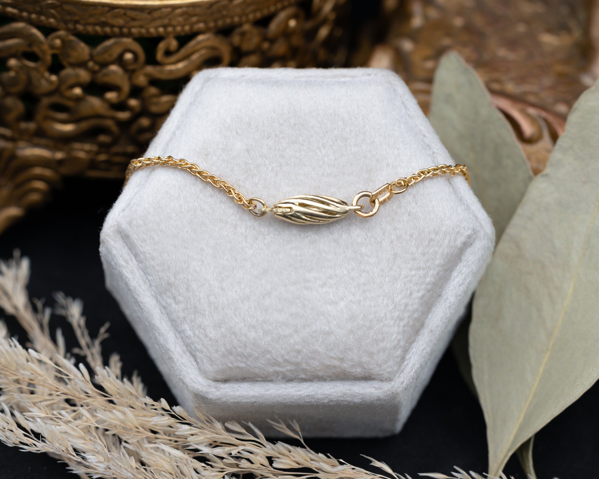 Gold chain on a hexagonal white jewelry display with decorative elements.