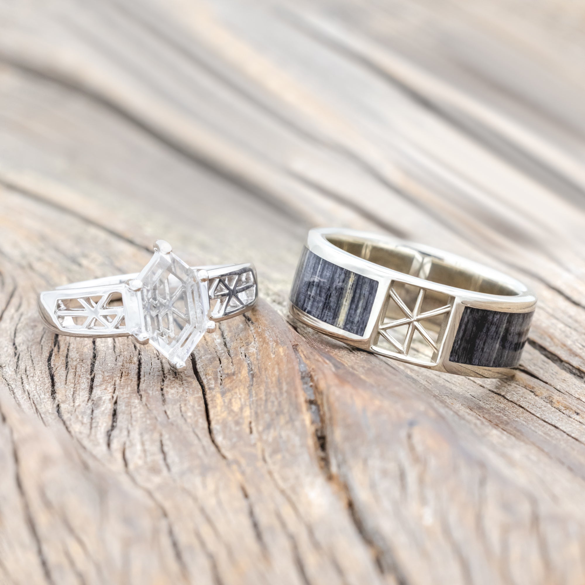 Two white gold rings with intricate designs on a wooden surface