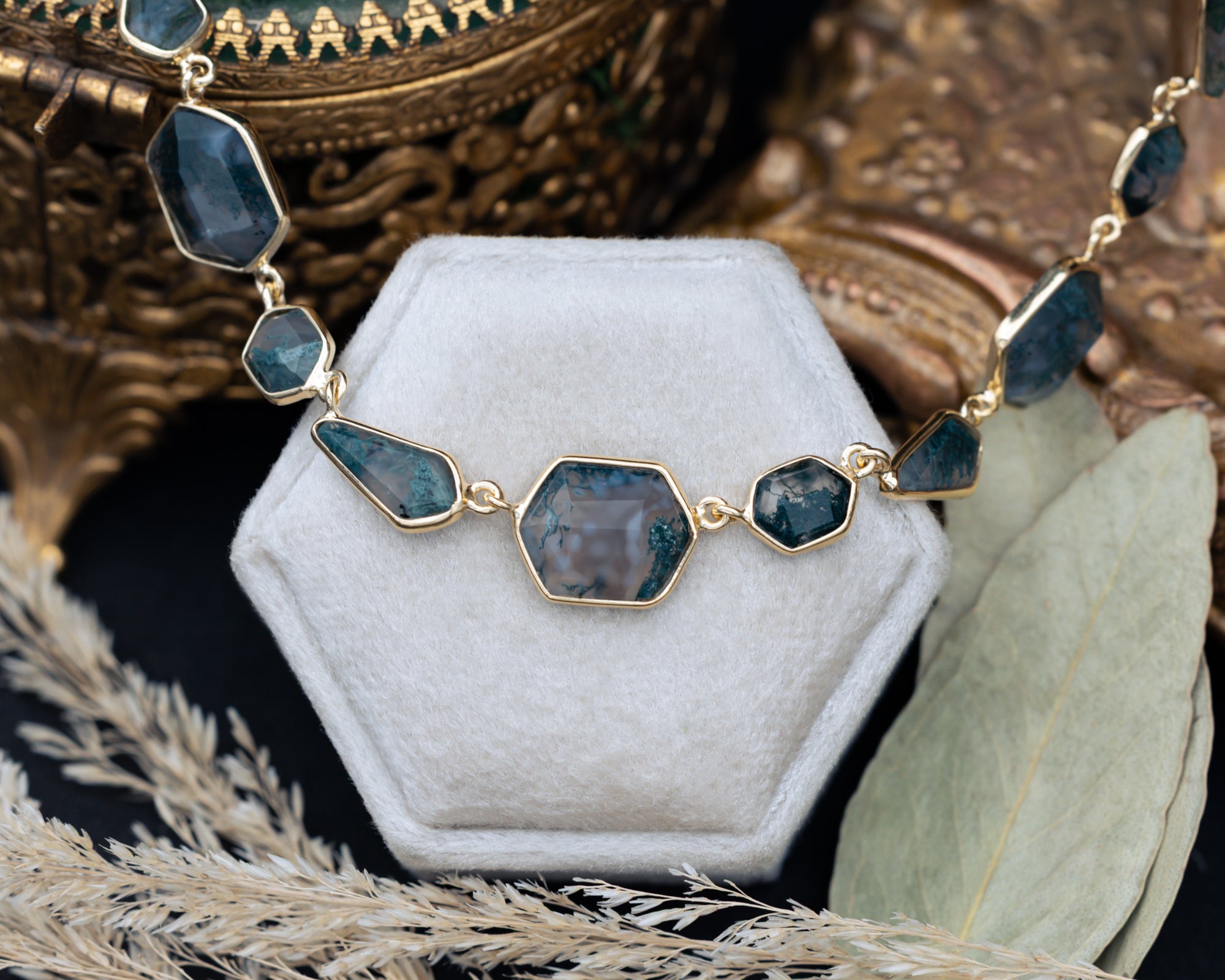 Necklace with moss agate pendants on a white stand with a decorative background