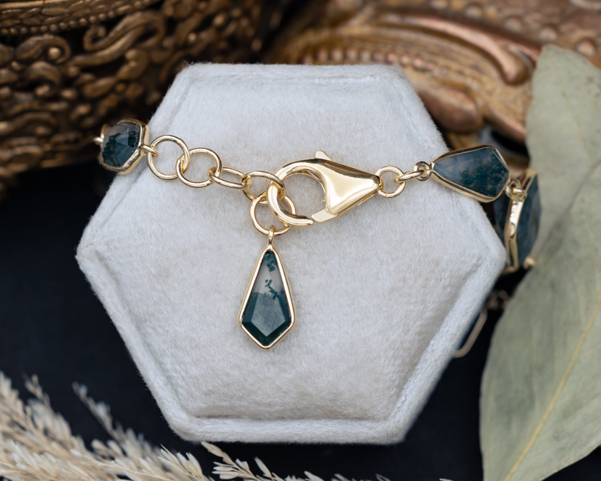 Balc clasp of moss agate necklace on a white stand with a decorative background
