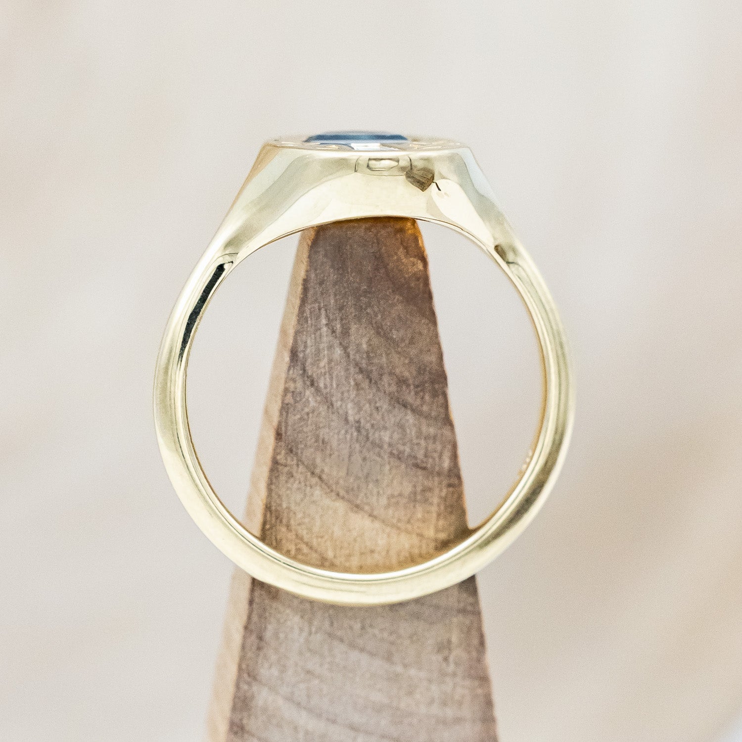 Side profile of a 14K yellow gold signet ring with a Montana sapphire half moon cap, tapered baguette diamond stem, and vines engraved on both sides.