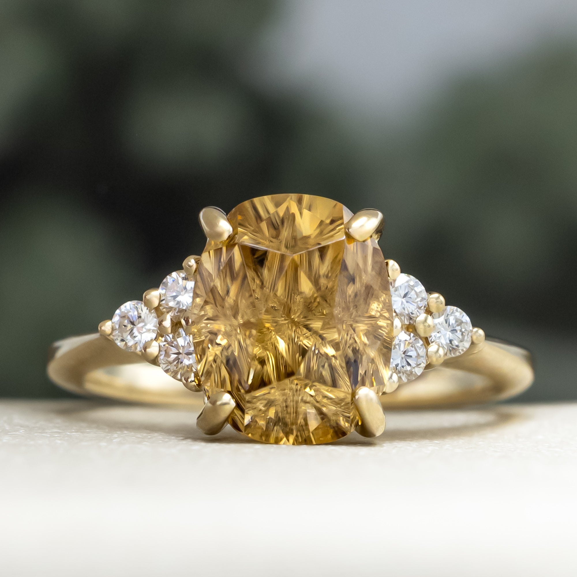 Gold ring with a large yellow zircon and diamond accents on a blurred background
