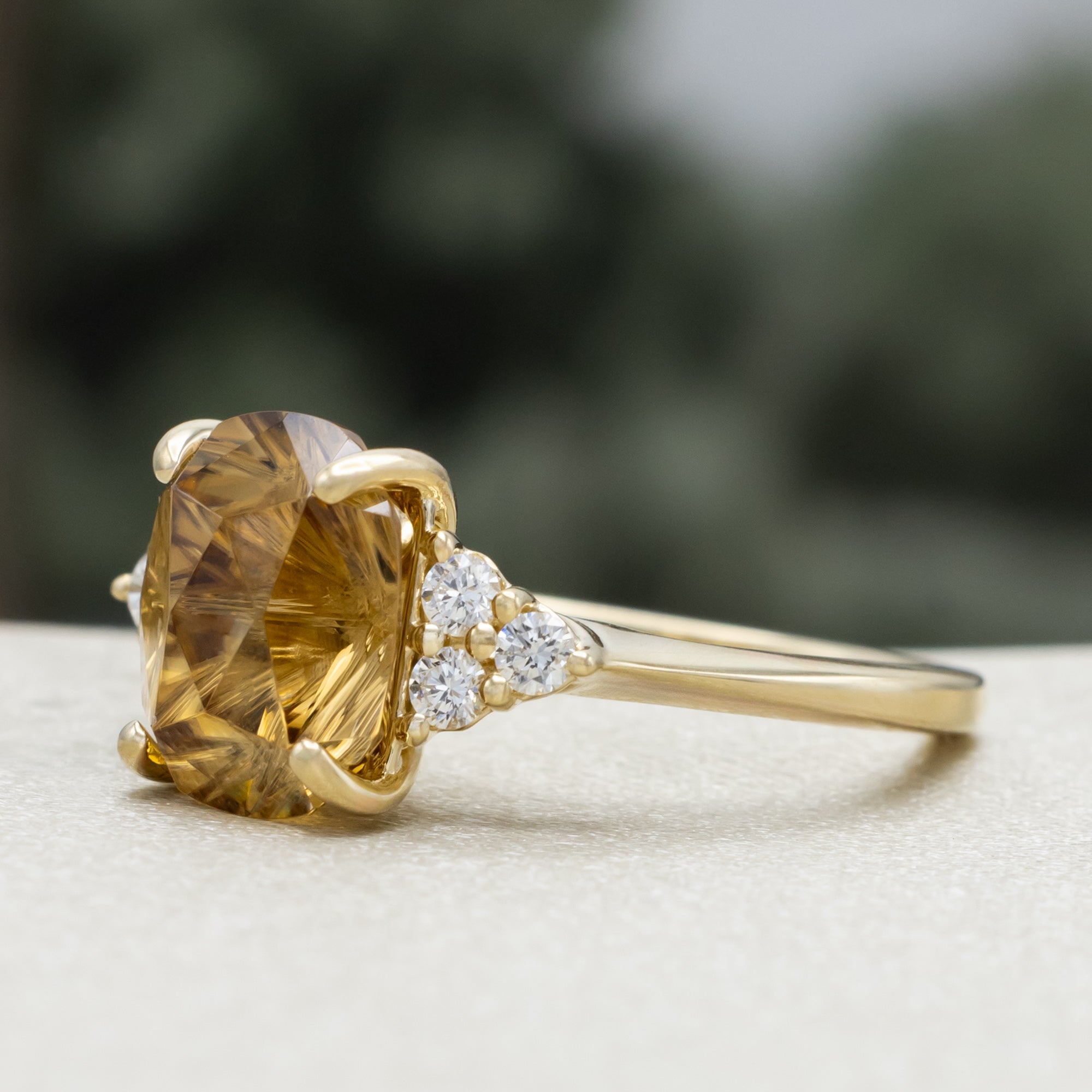 Gold ring with a large yellow zircon and diamond accents on a blurred background