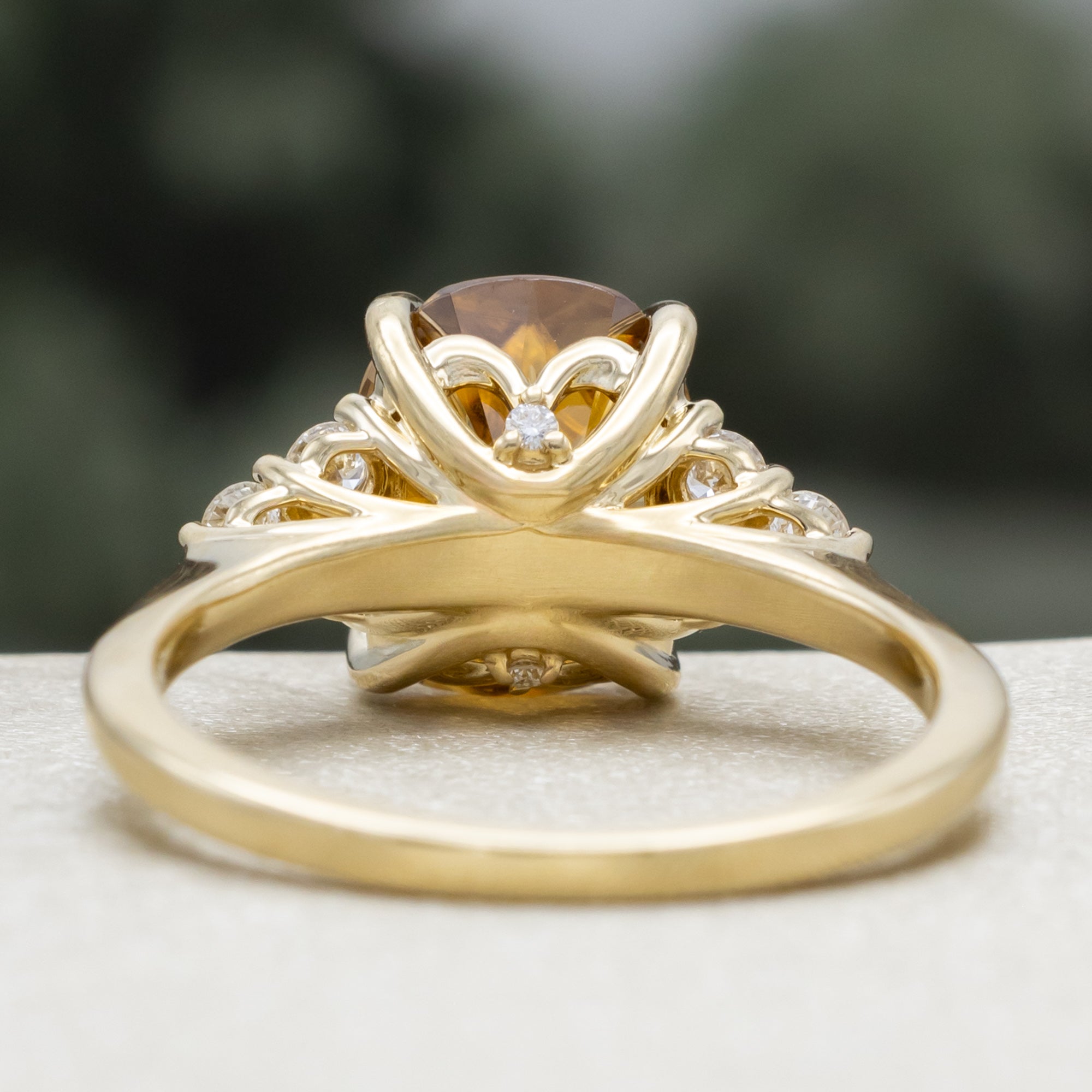 Gold ring with a large yellow zircon and diamond accents on a blurred background
