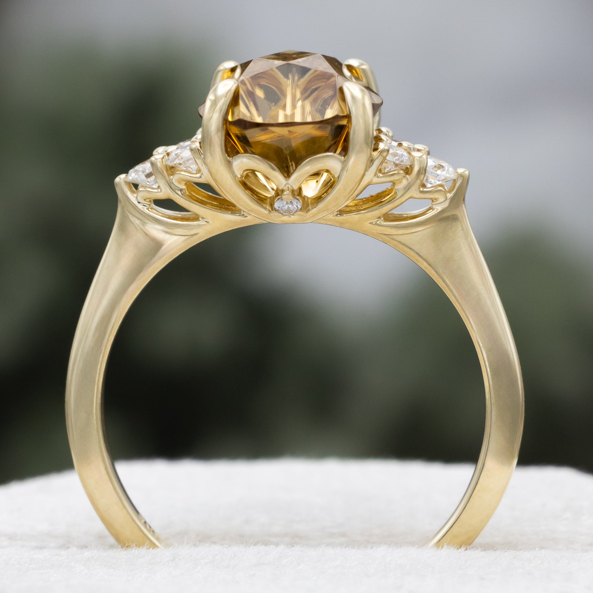 Gold ring with a large yellow zircon and diamond accents on a blurred background