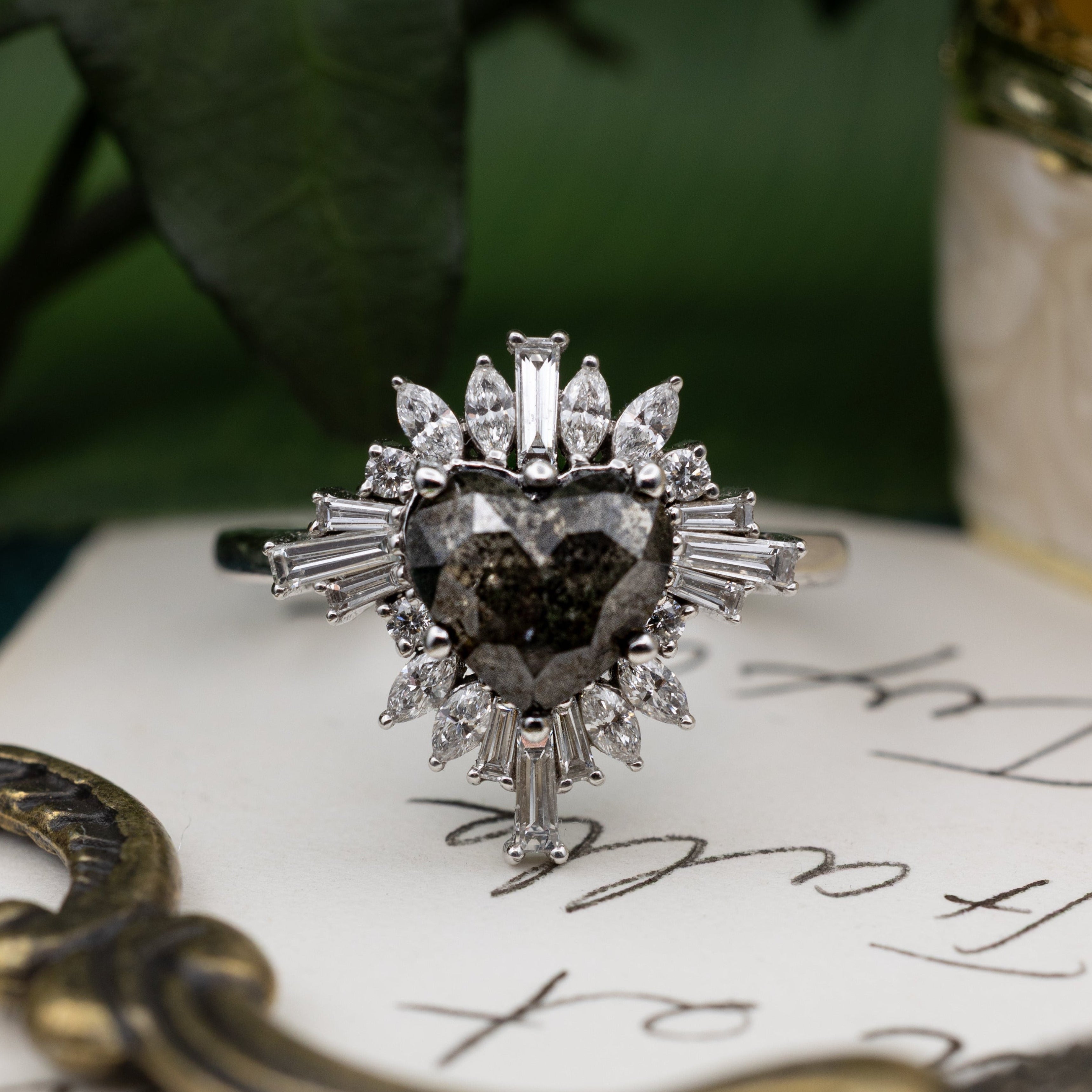 Heart-shaped salt & pepper diamond ring on a piece of paper with decorative elements