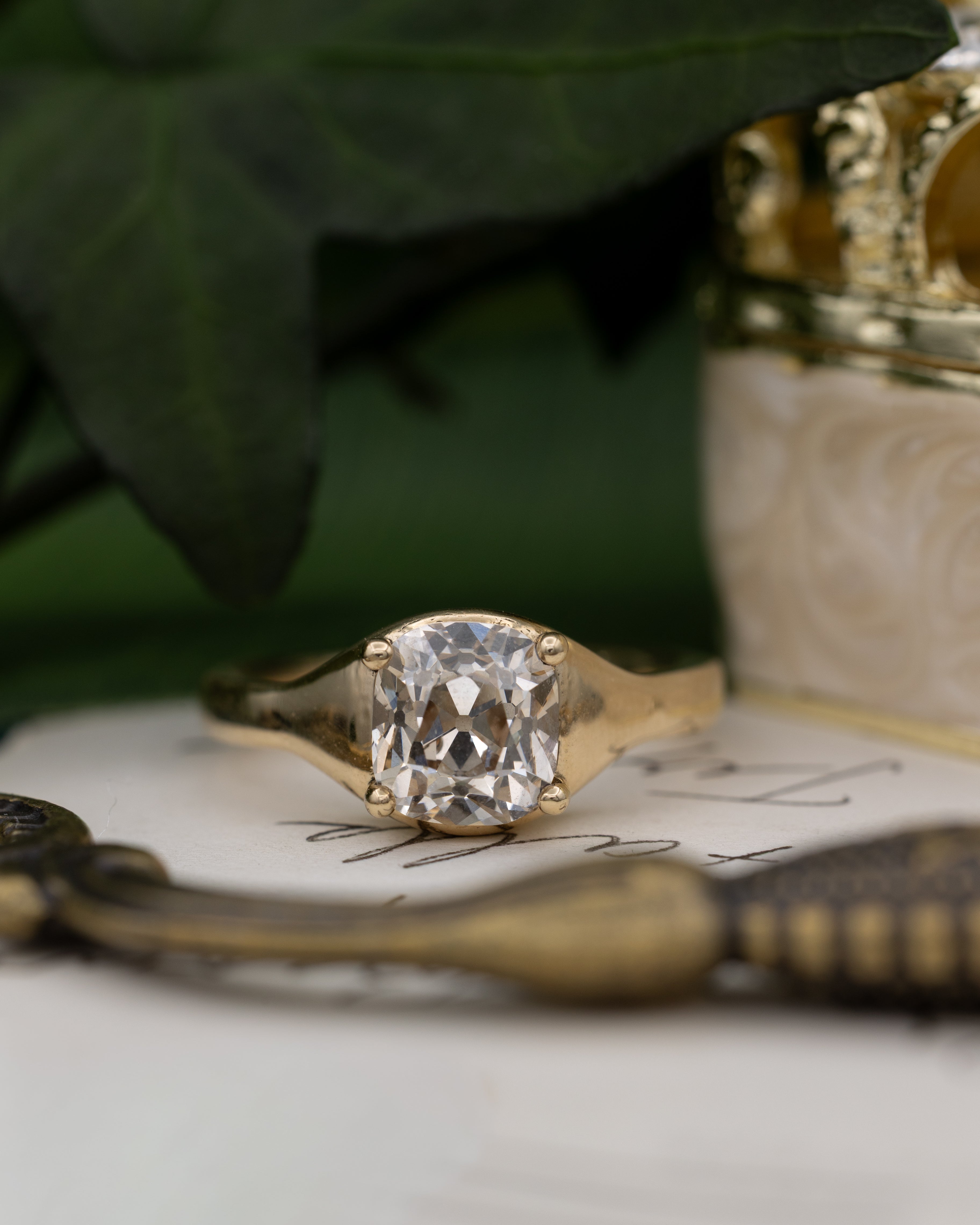 Yellow gold ring with diamond on a vintage letter against a blurred green background