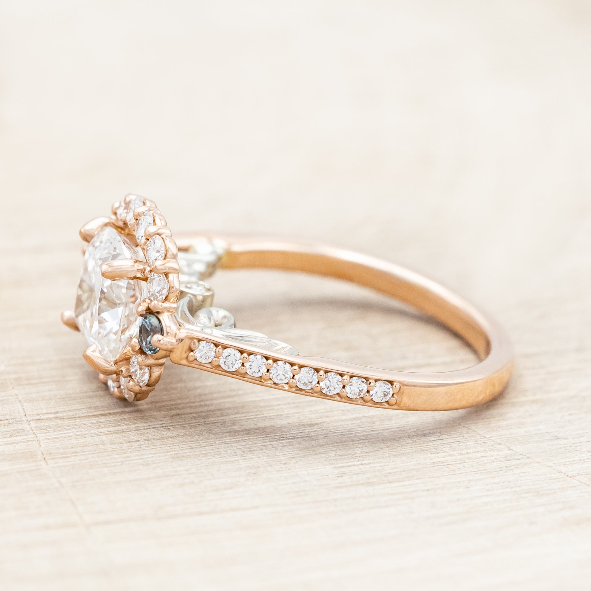 Rose gold ring featuring a large lab diamond with diamond and sapphire accents on a neutral background