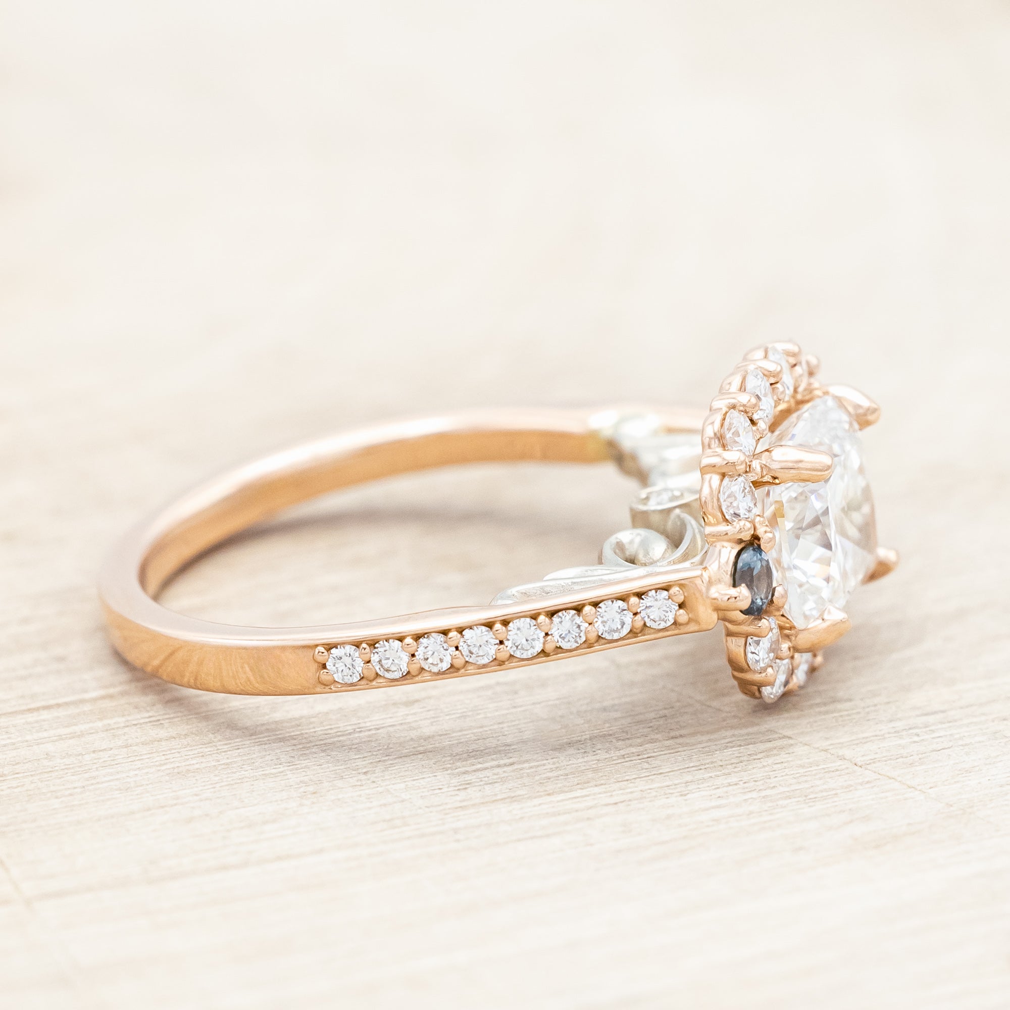 Rose gold ring featuring a large lab diamond with diamond and sapphire accents on a neutral background