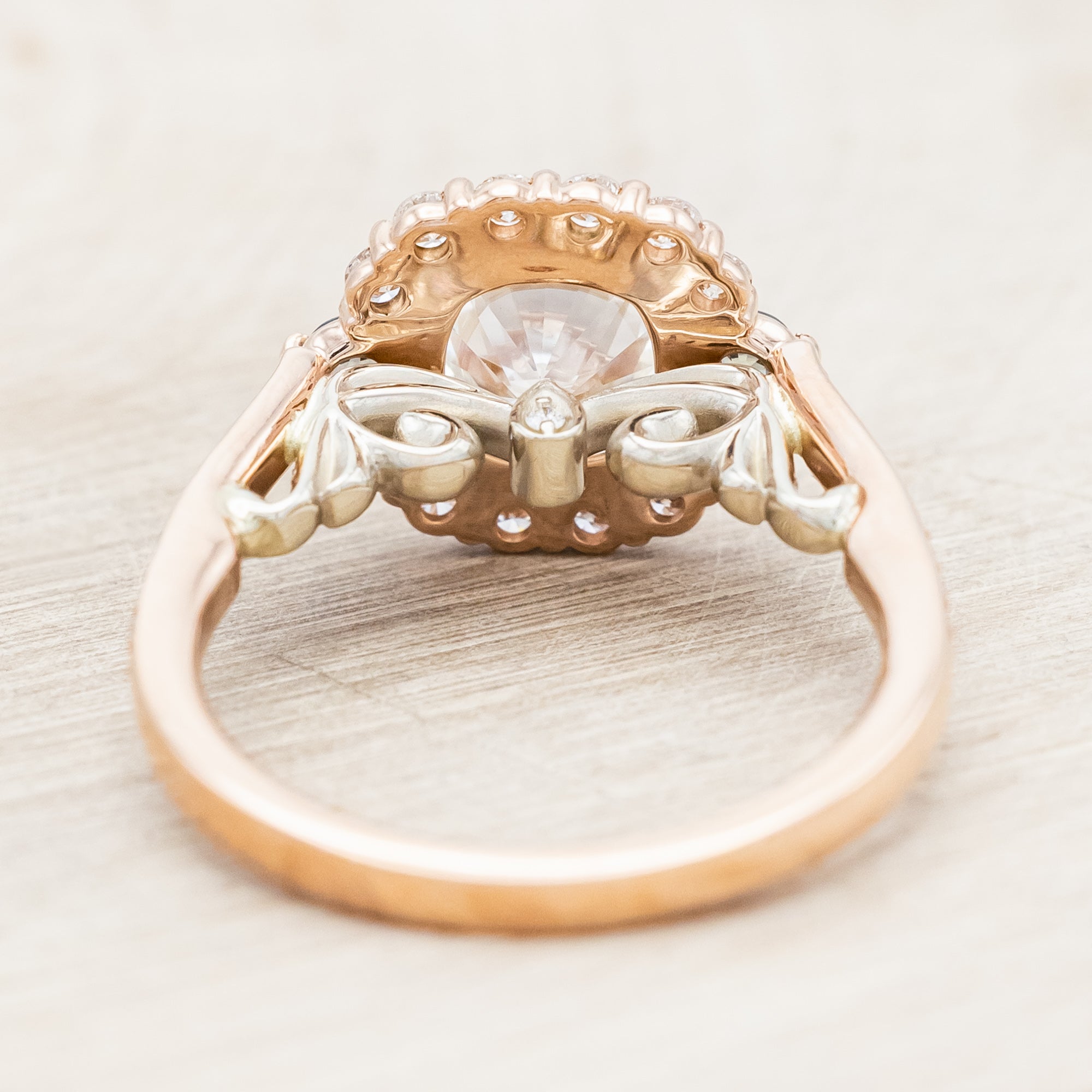 Rose gold ring featuring a large lab diamond with diamond and sapphire accents on a neutral background