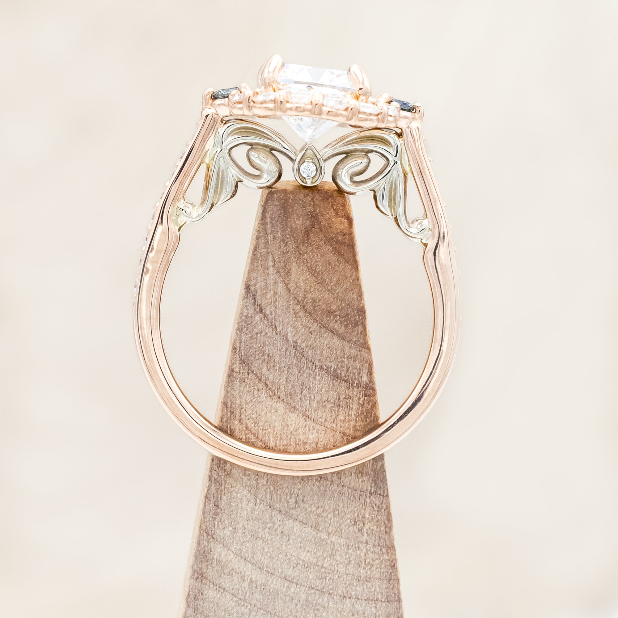 Rose gold ring featuring a large lab diamond with diamond and sapphire accents on a neutral background