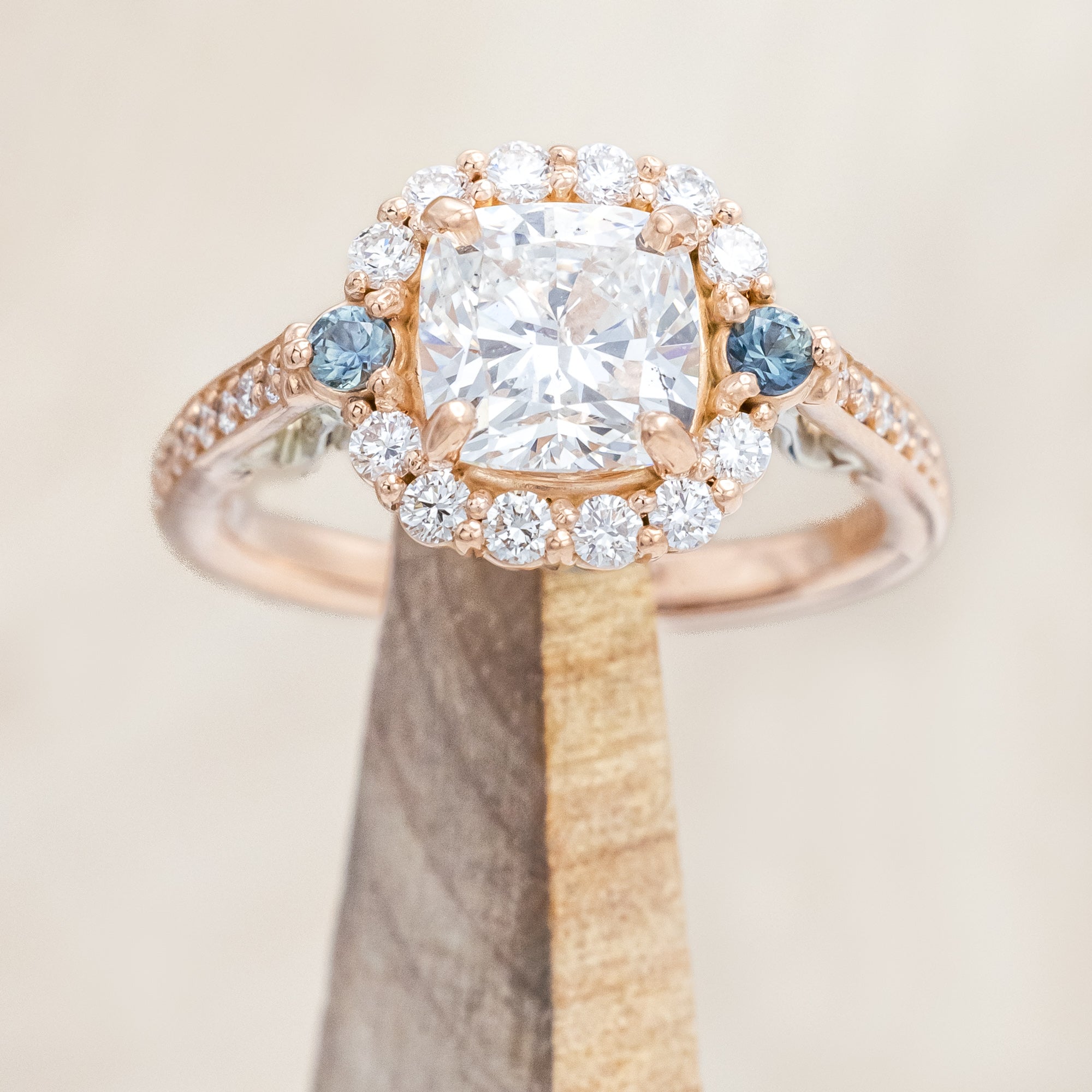 Rose gold ring featuring a large lab diamond with diamond and sapphire accents on a neutral background