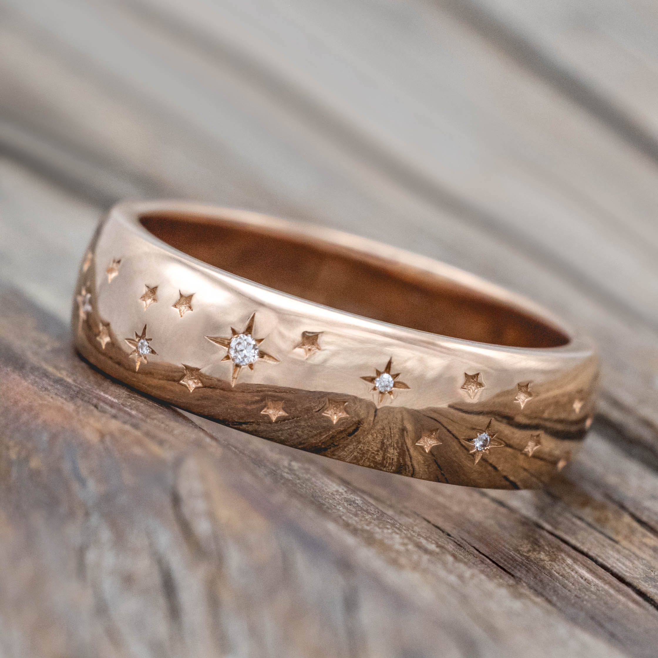14K rose gold ring with star designs inset with diamonds on a wooden surface