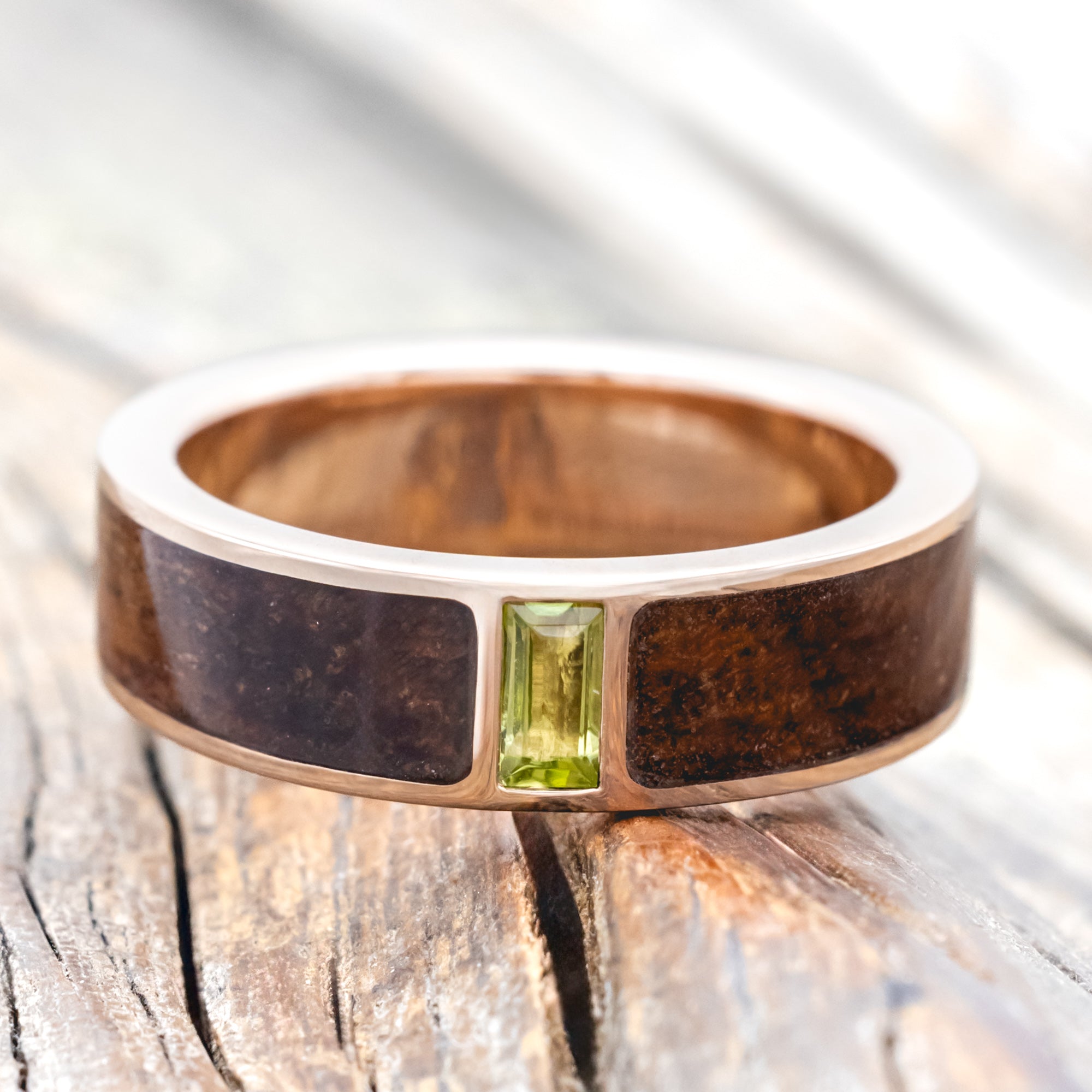 Koa wood ring with a green peridot on a wooden surface