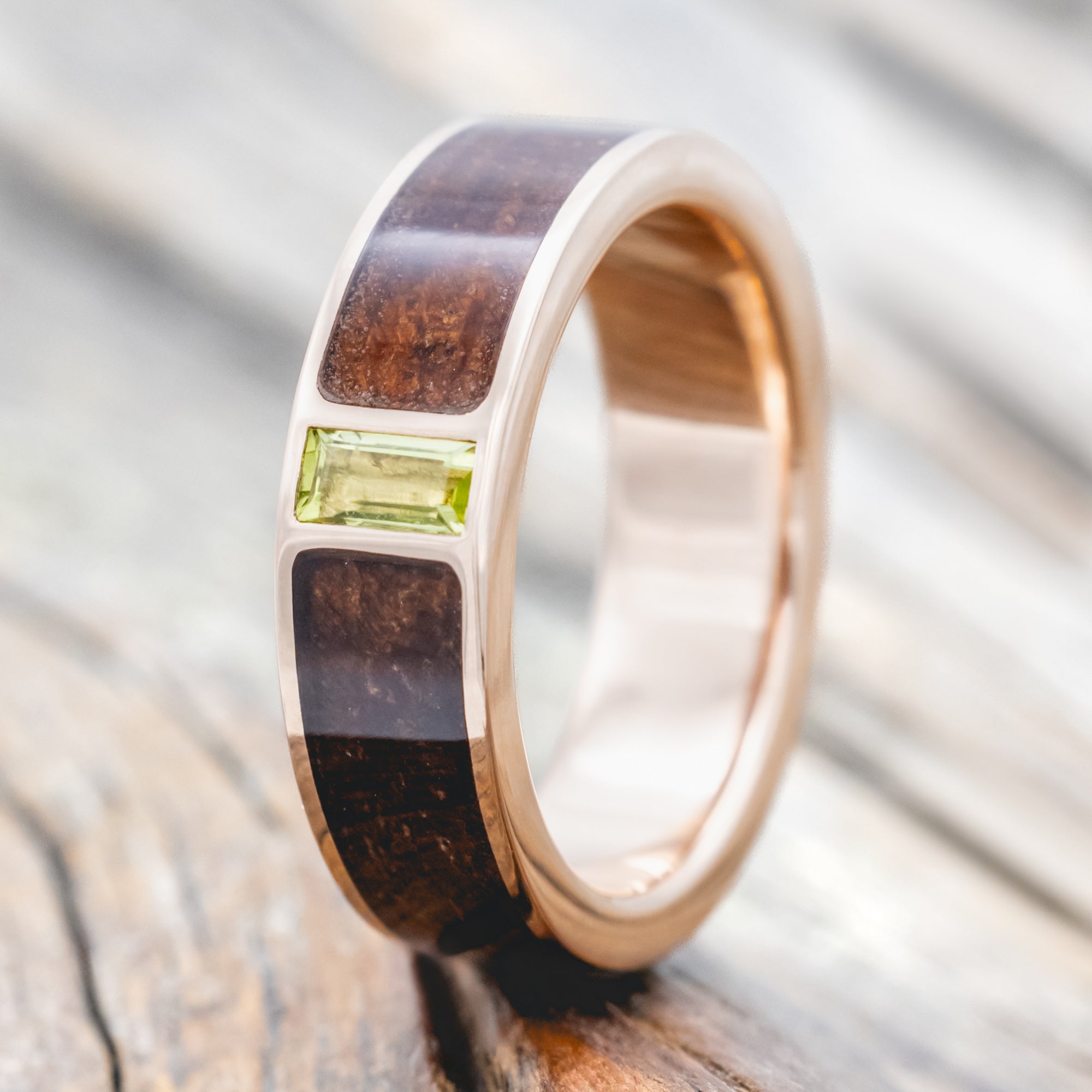 Koa wood ring with a green peridot on a wooden surface