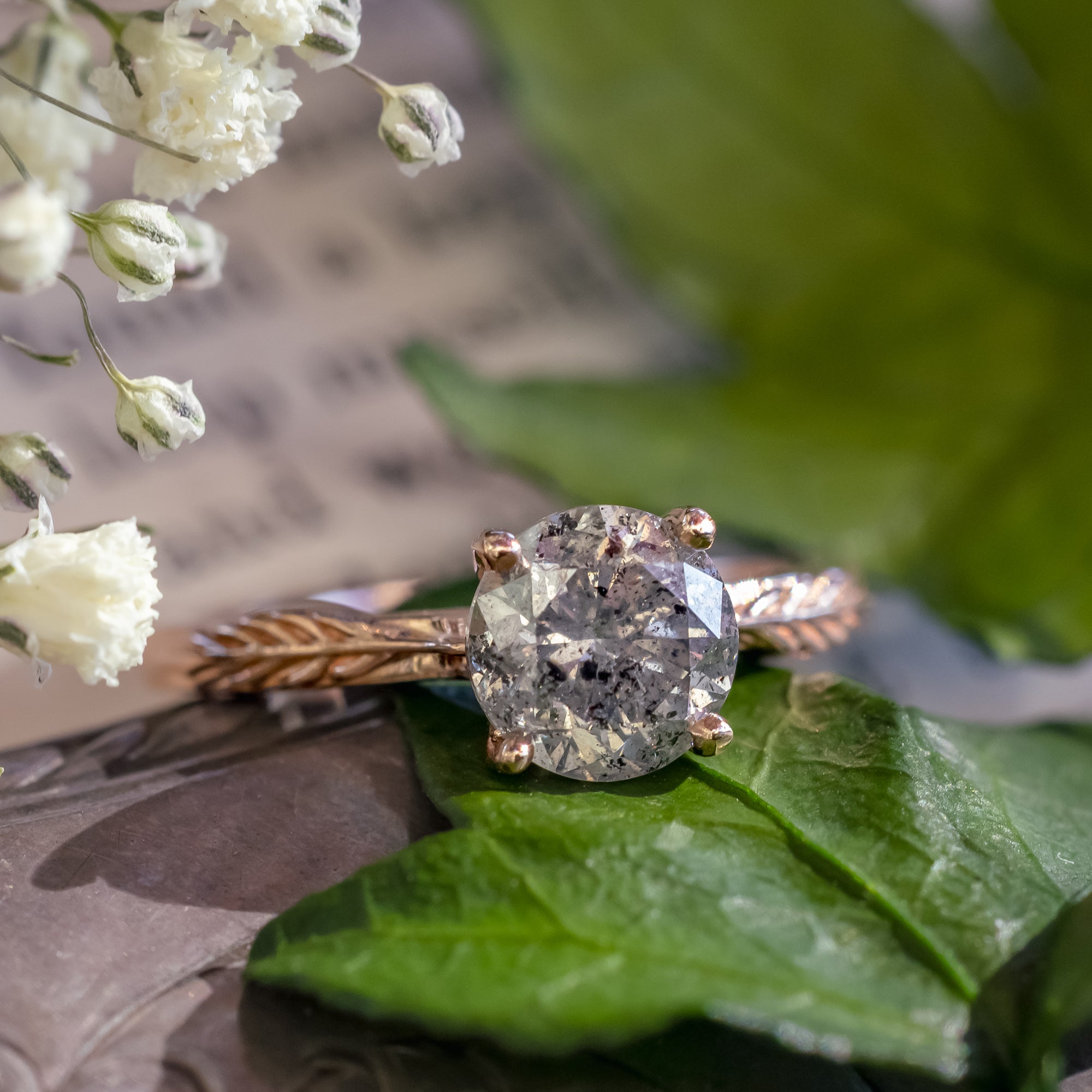 Rose gold ring with salt & pepper diamond on a blurred decorative surface