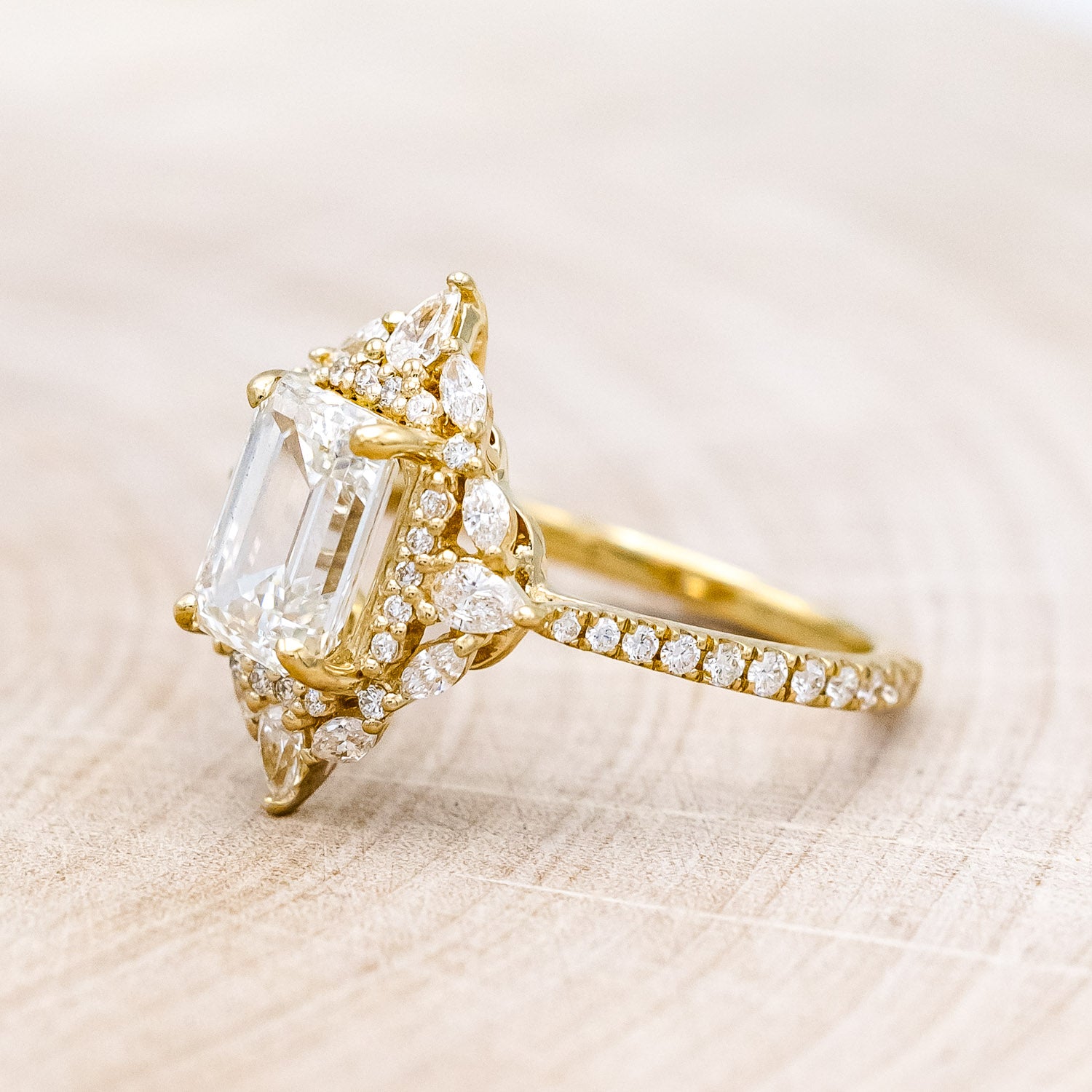 Side view of "North Star" - emerald cut diamond women's engagement ring with a diamond halo and accents on a 14K yellow gold band