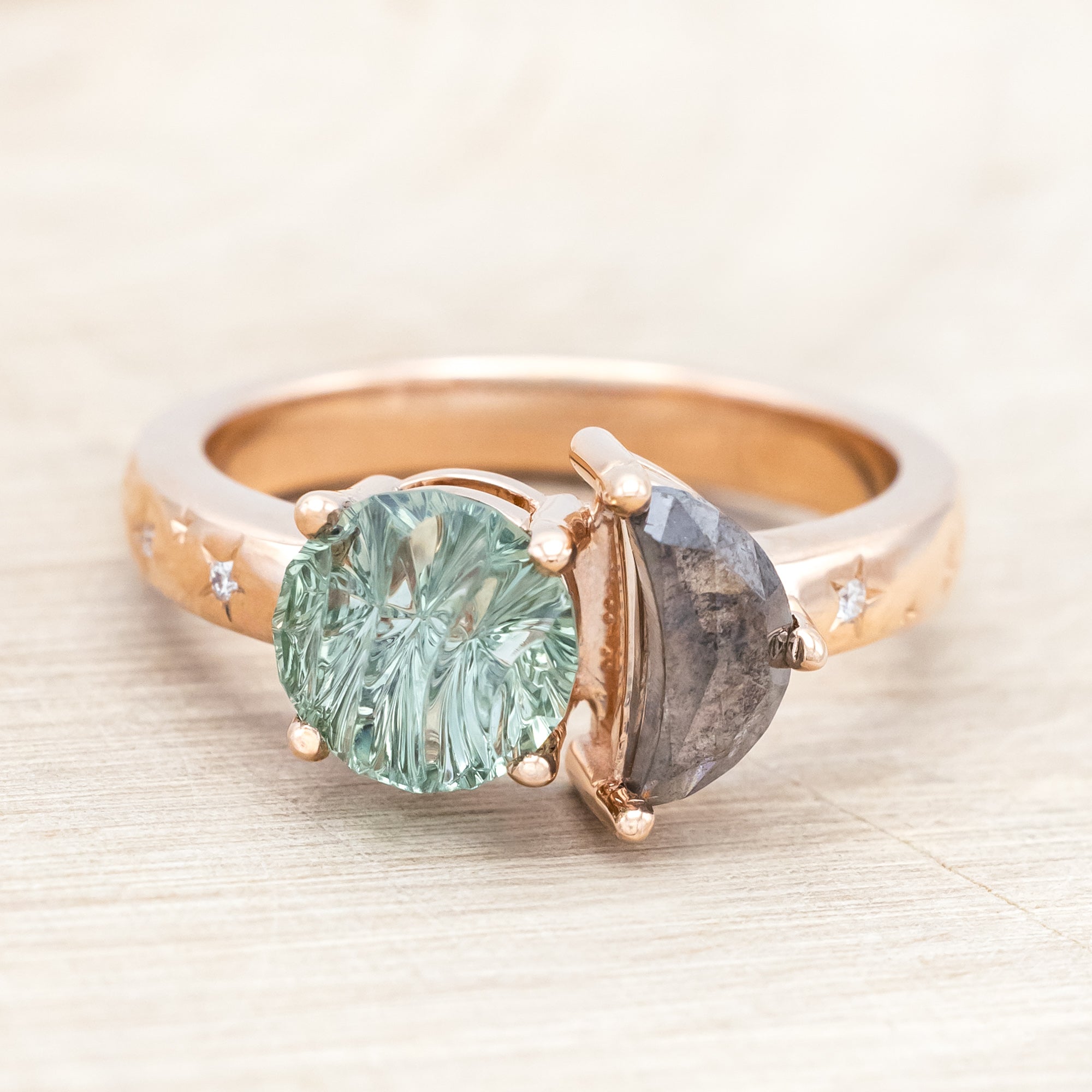 Ring with green sapphire and salt & pepper diamond and rose gold band on a neutral background