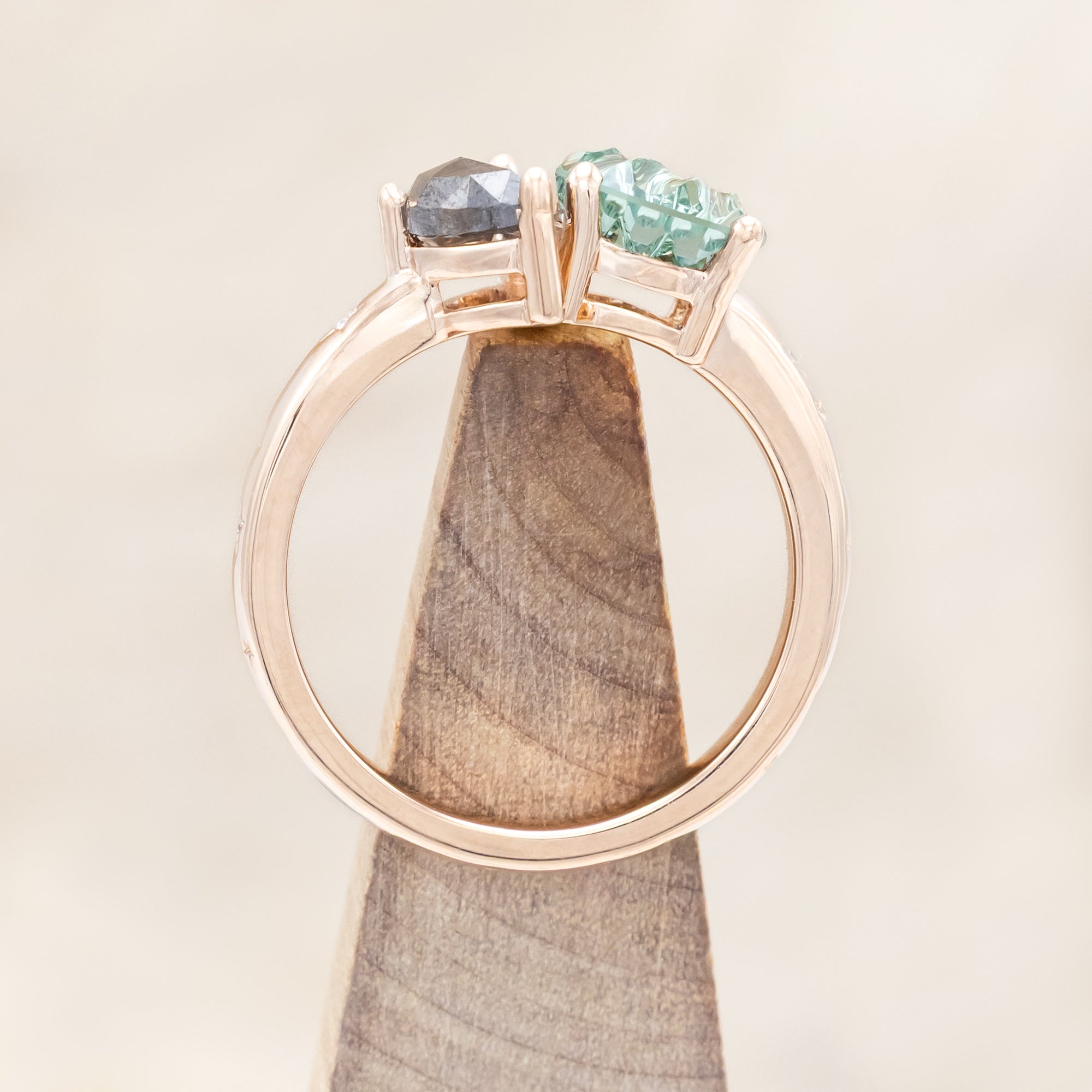 Ring with green sapphire and salt & pepper diamond and rose gold band on a neutral background