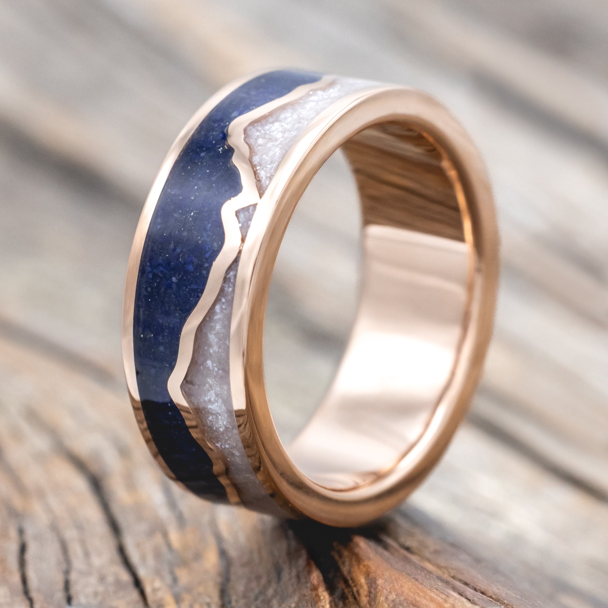 Rose gold ring with lapis lazuli and diamond dust inlay on a wooden surface