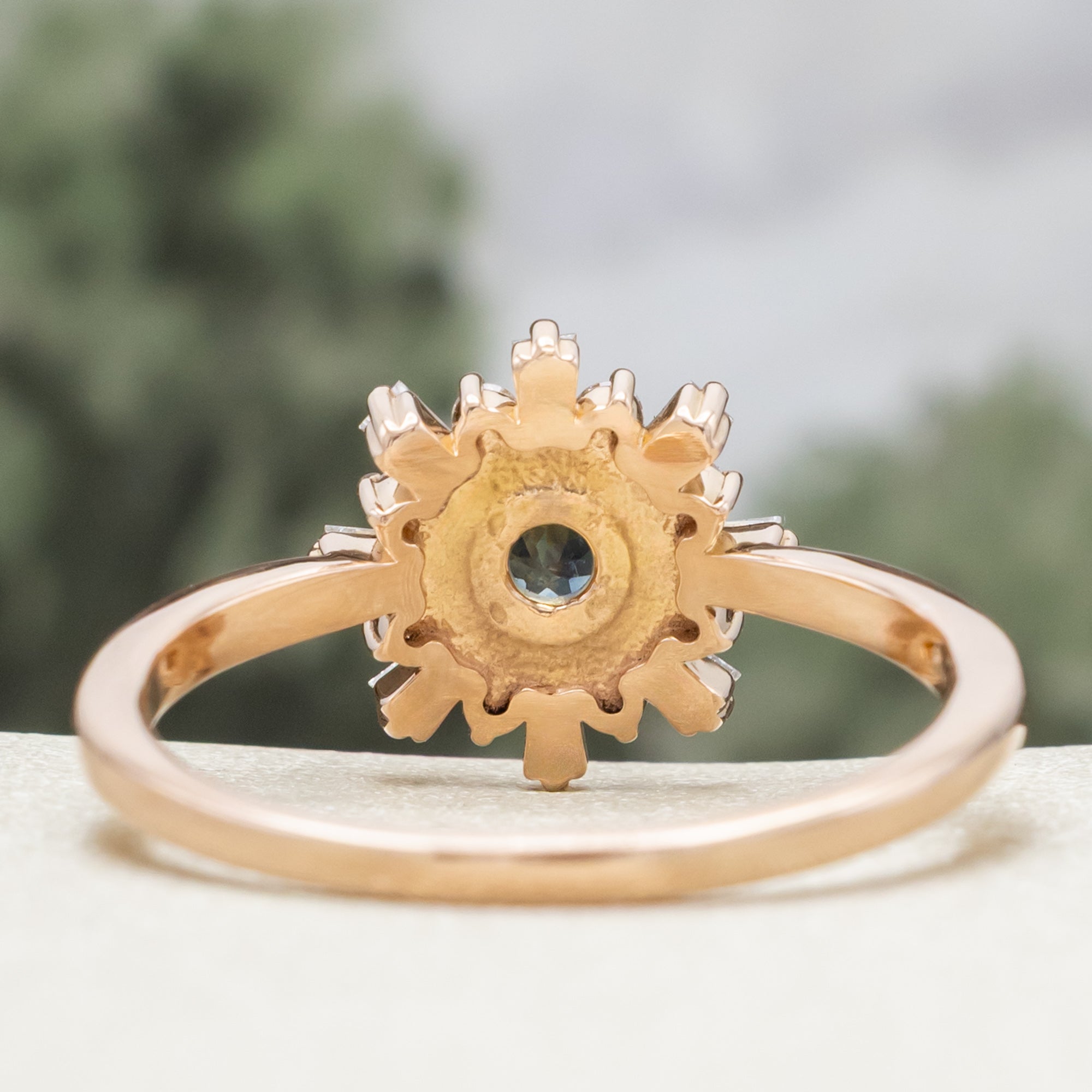 Rose gold ring with a Montana sapphire and diamond accents on a neutral backgron