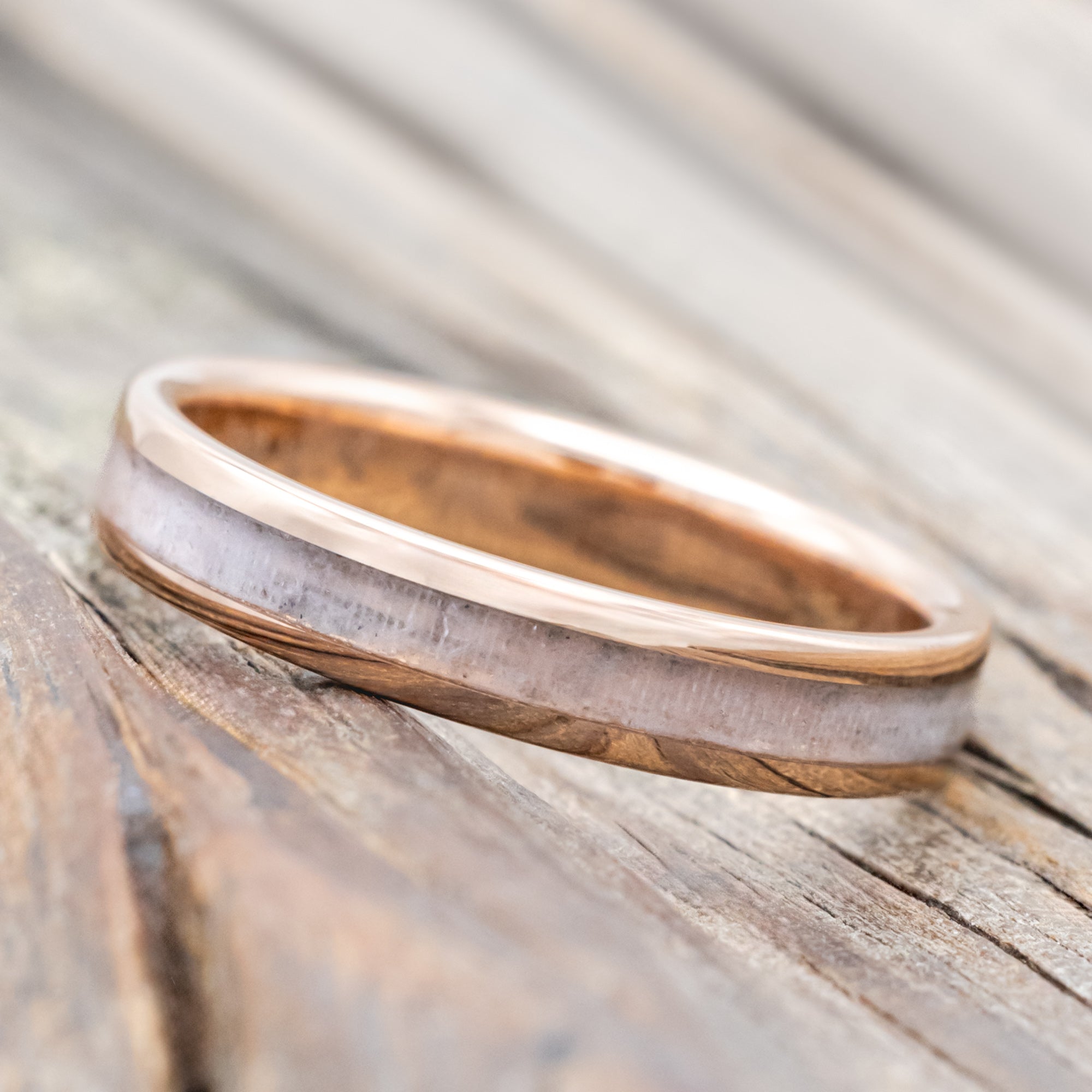 Rose gold ring with wedding dress inlay on a wooden surface