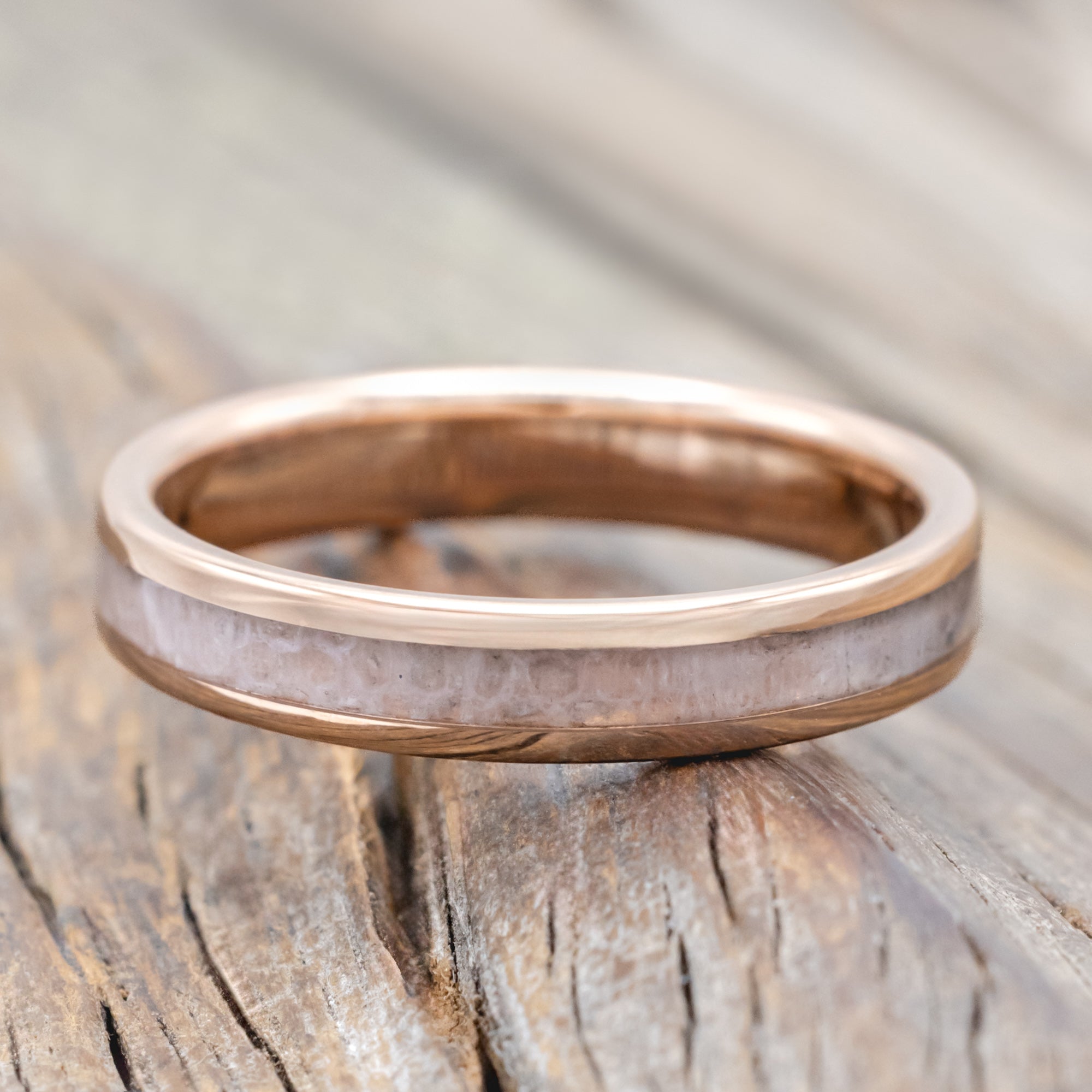 Rose gold ring with wedding dress inlay on a wooden surface