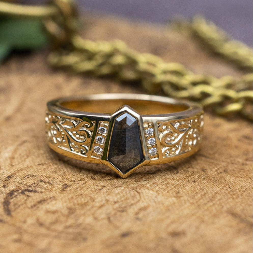 Gold ring with a black gemstone on a textured surface