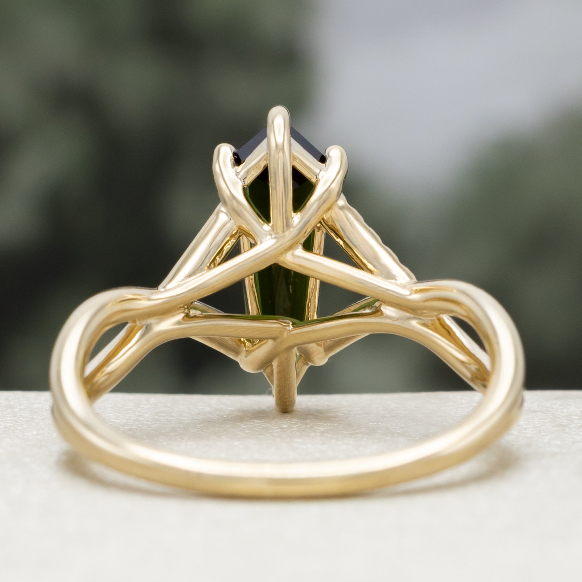 Gold ring with a green tourmaline and diamond accents against a blurred green background