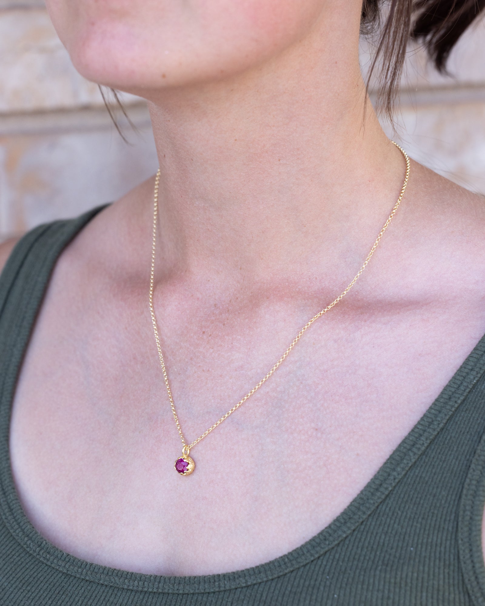 Gold necklace with a ruby worn by a person