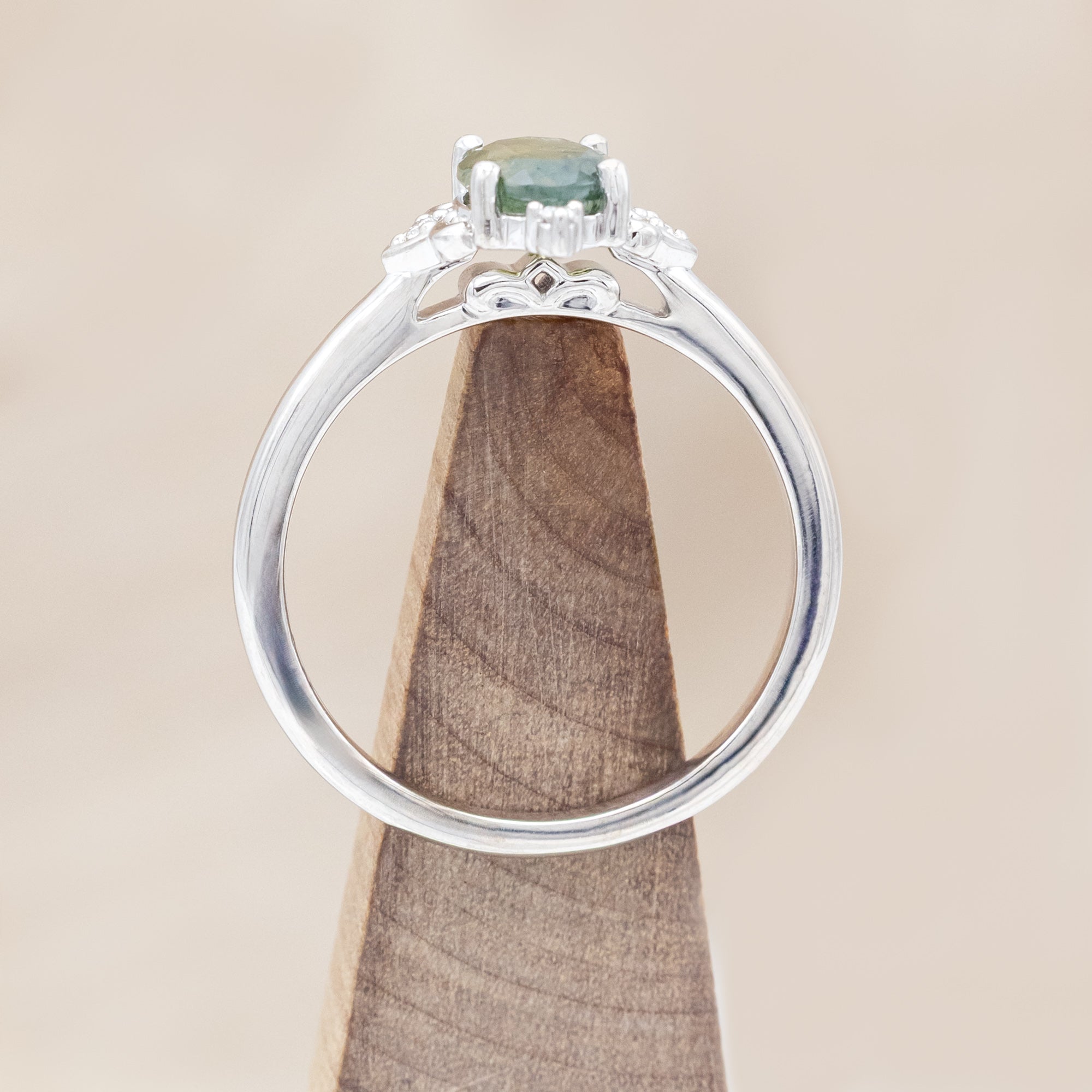 14K white gold engagement ring with moss agate and diamond accents on a light wooden surface