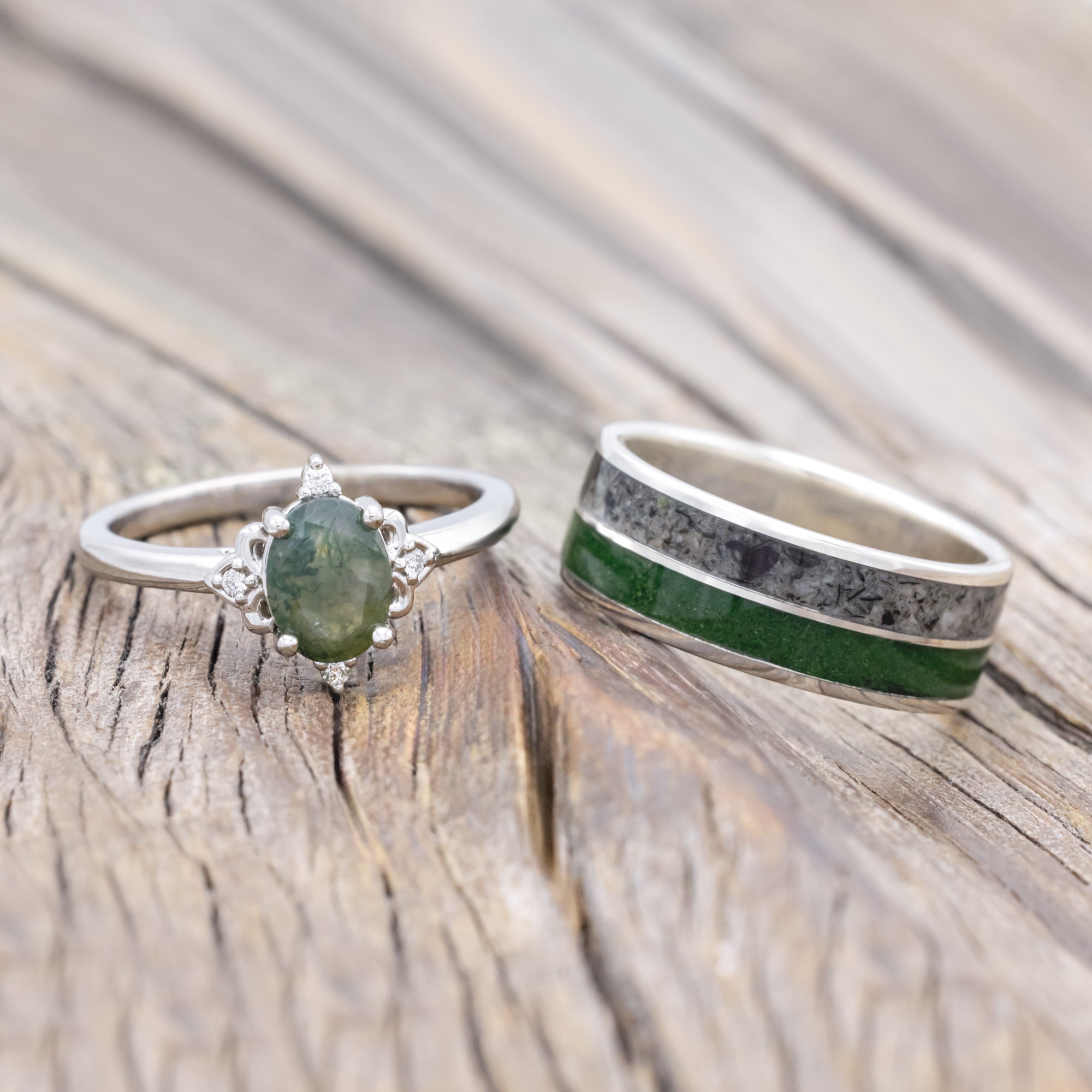 Moss agate engagement ring with moss and moonstone wedding ring on a wooden surface