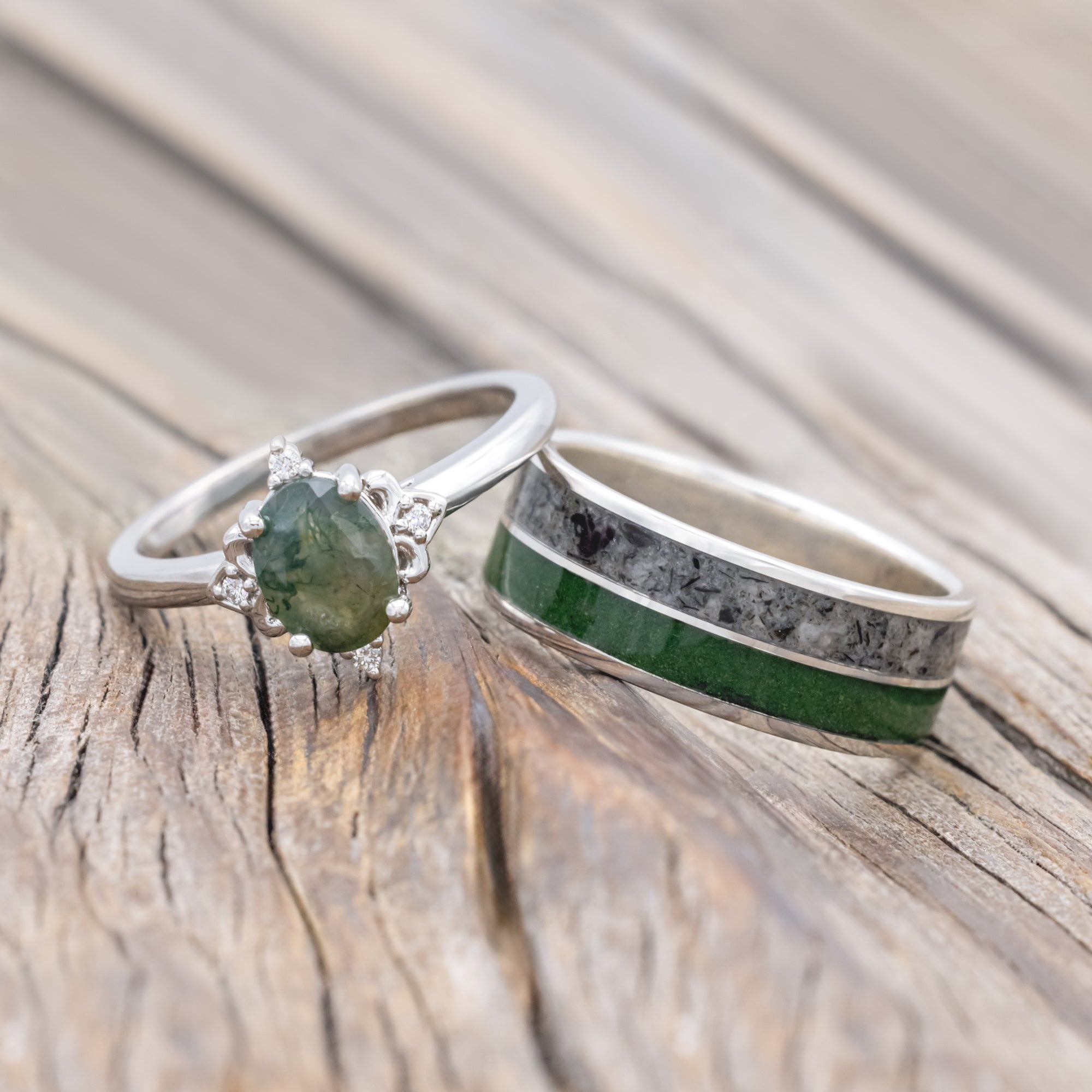 Moss agate engagement ring with moss and moonstone wedding ring on a wooden surface