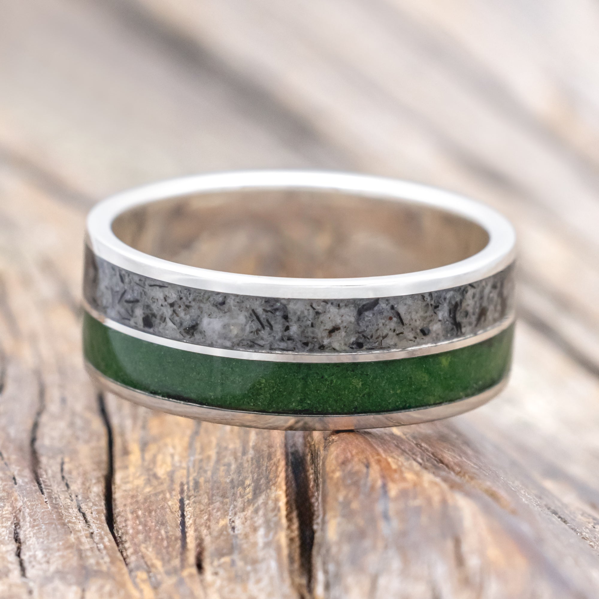 Silver ring with moss and moonstone inlay on a wooden surface