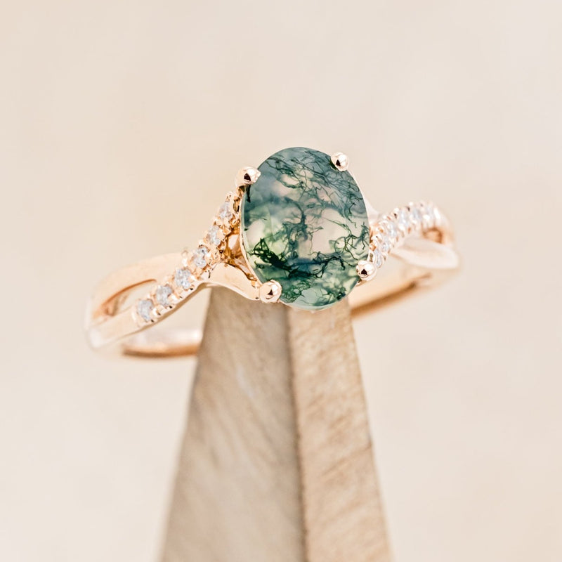 Shown here is "Roslyn", an oval moss agate women's engagement ring with diamond accents, on stand front facing. Many other center stone options are available upon request.