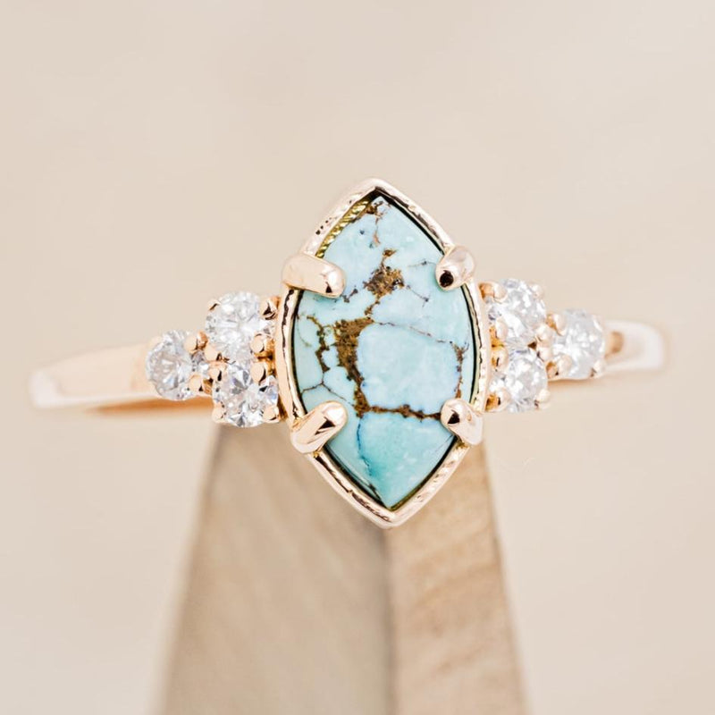 Shown here is "Raya", a turquoise women's engagement ring with diamond accents, on stand front facing. Many other center stone options are available upon request.