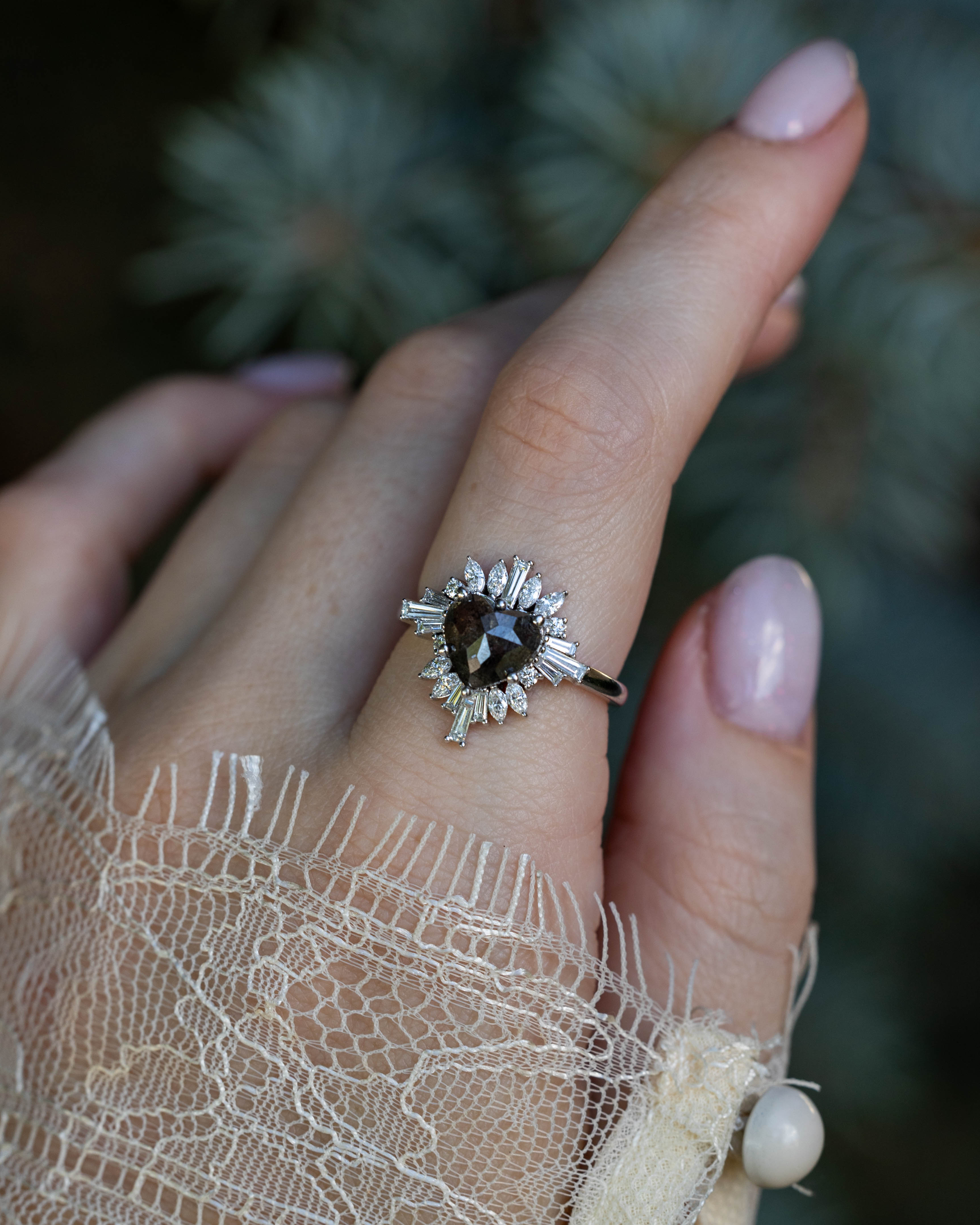 On hand of "Autumn" - women's engagement ring with heart cut salt & pepper diamond and diamond halo in 14K white gold