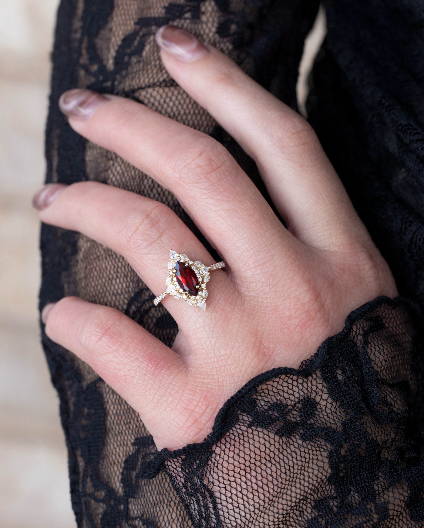 Hand wearing a ring with a red garnet against a black lace background