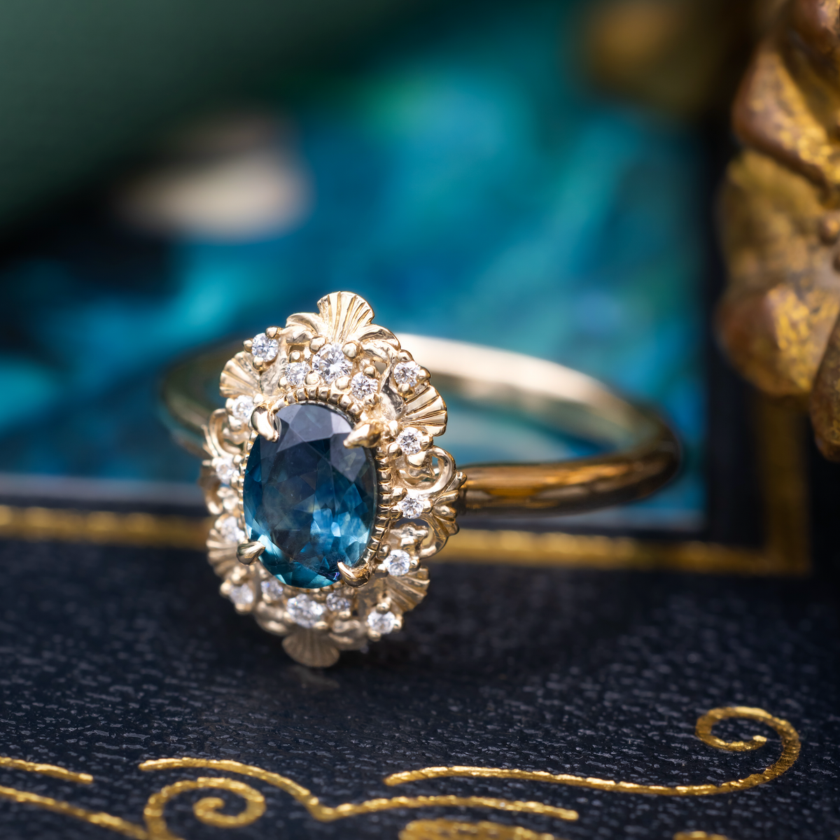 A gold ring with Montana sapphire center stone and diamond accents against a dark moody background