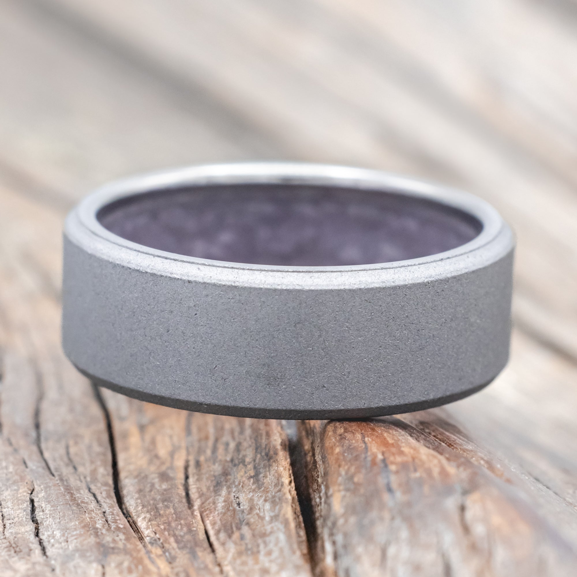 titanium ring with amethyst lining on a wooden surface against a blurred background